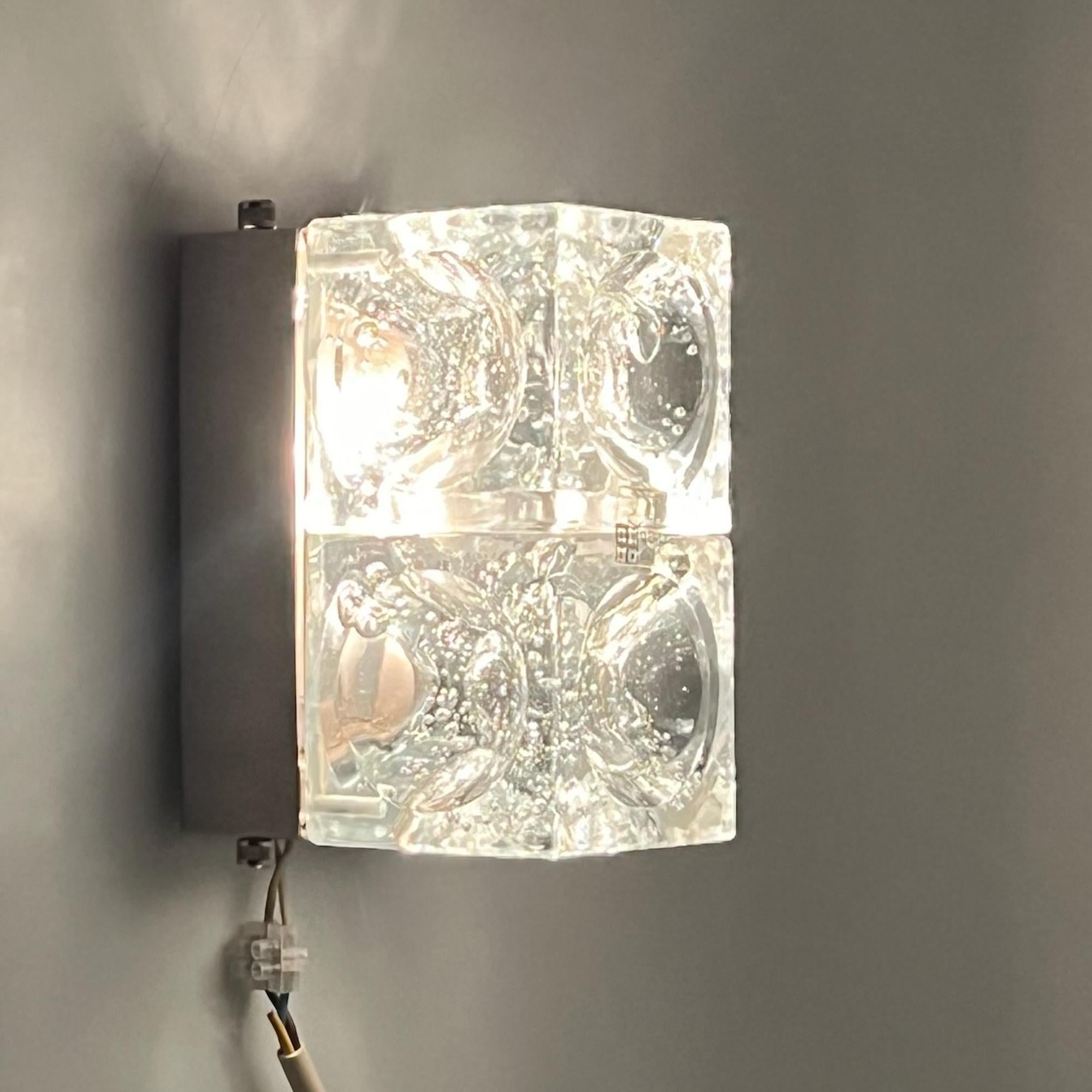 Modèle rare et distinctif de la gamme emblématique Poliarte, la lampe Icone a été méticuleusement fabriquée par le maître Albano Poli. Ce chef-d'œuvre présente deux cubes concaves en verre bulle sertis dans une base métallique avec des vis en acier