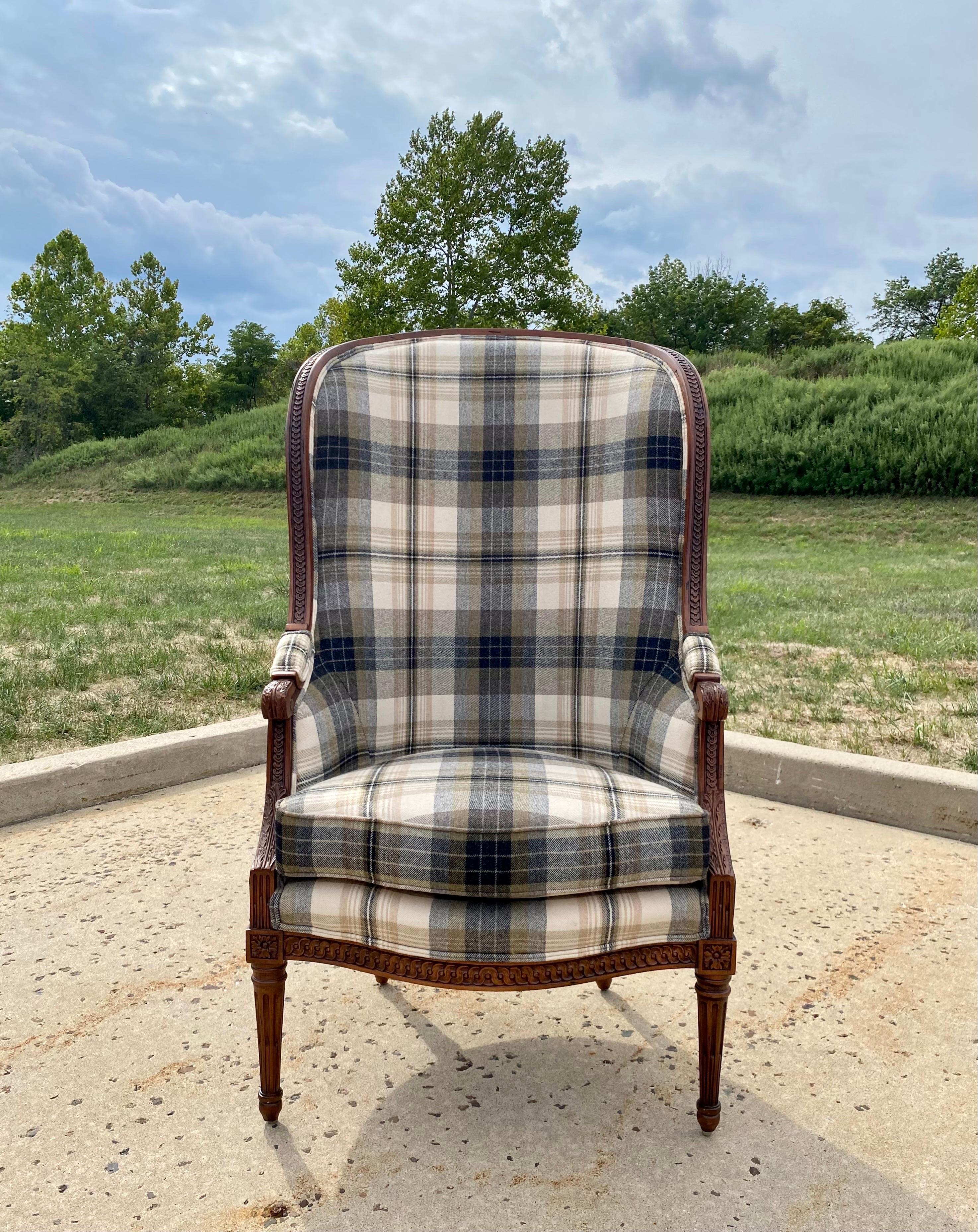 Iconic Ralph Lauren Home tall bergère arm chair upholstered in a classic wool plaid upholstery with contrasting embossed black leather snakeskin. This dramatic balloon shaped porters chair has a beautifully carved wood frame and an exposed back that