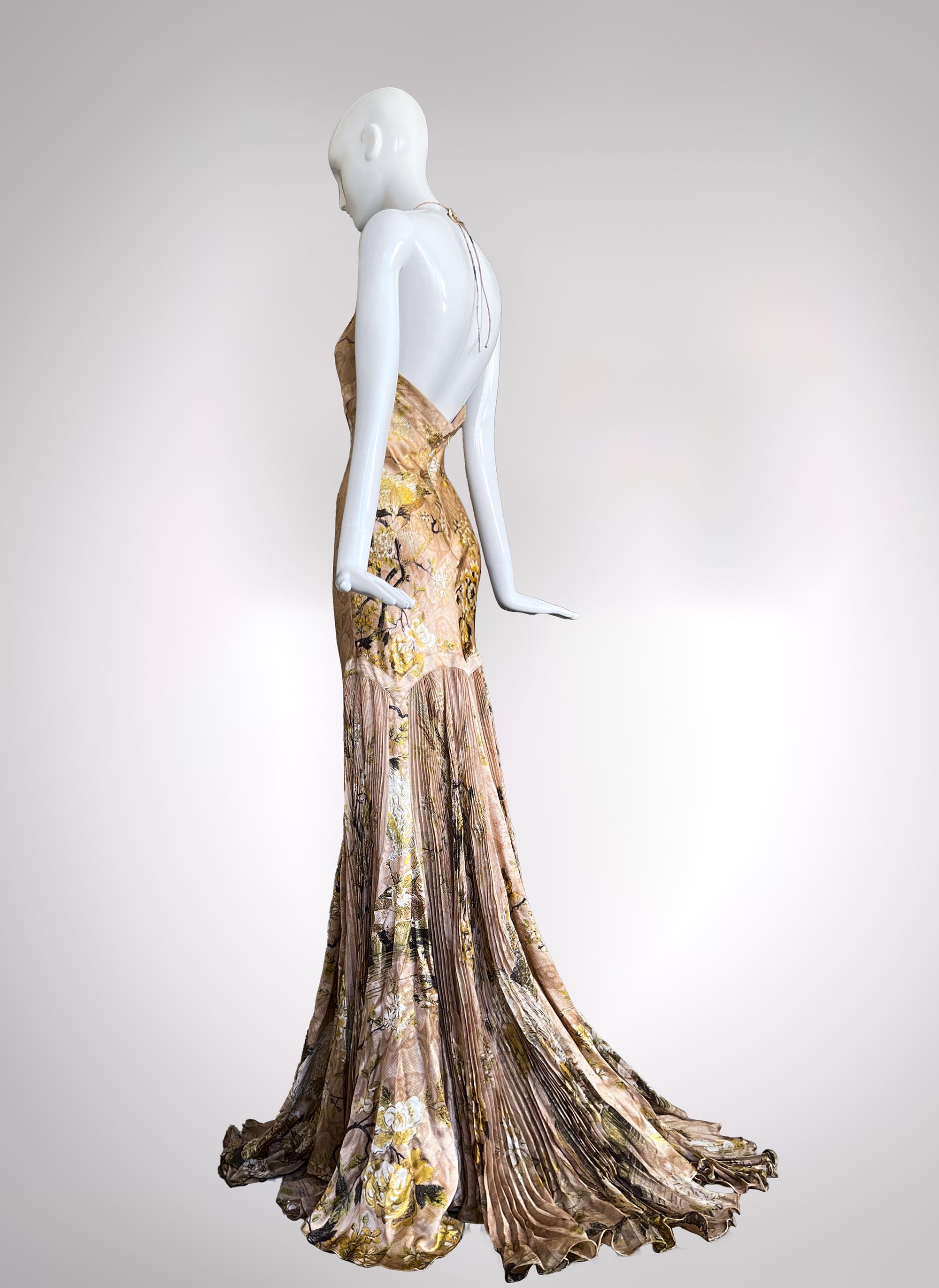 A Roberto Cavalli Masterpiece from 2006
Drenched in the opulence of gilded romance, this Roberto Cavalli silk evening gown is a red-carpet reverie. A symphony of delicate florals, liquid gold accents, and ethereal draping, it embodies Cavalli’s
