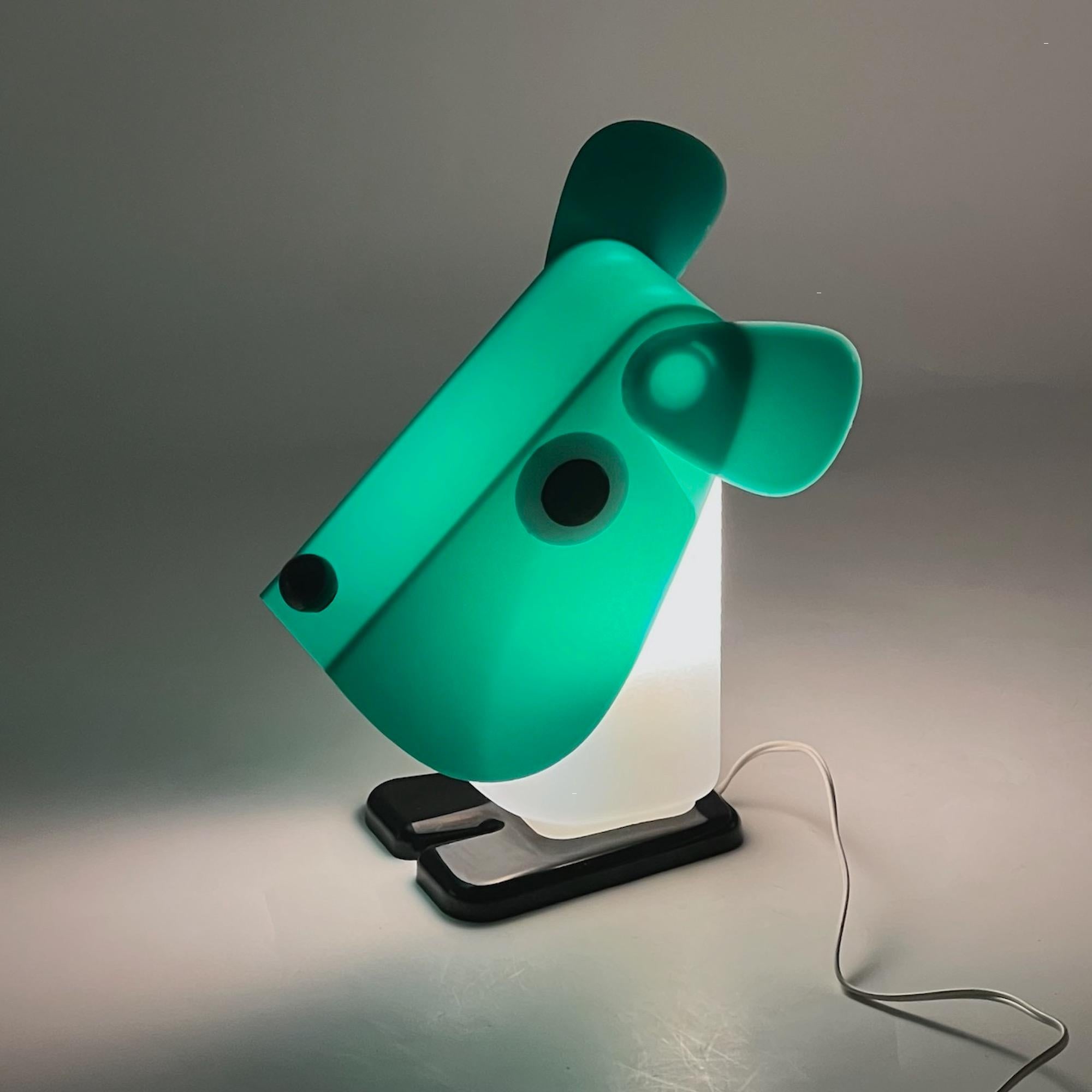 Designed in the 1970s by Fernando Cassetta for Tacman Manara, the Rufus the Dog lamp is a standout example of functional and innovative design. Constructed entirely of durable plastic, it features a striking green, white, and black