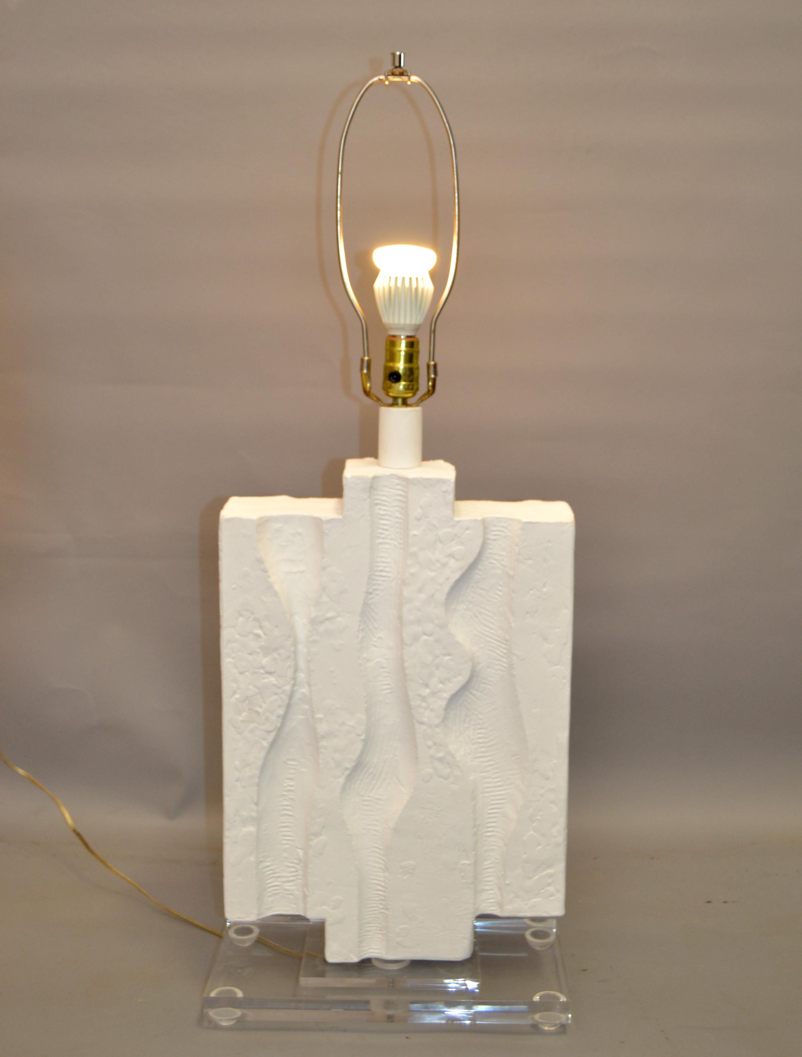 Mid-Century Modern table lamp in white Gesso Finish.
Plaster undertone with textured pattern a chrome neck.
Lamp is supported by 2 inches rectangle Acrylic Base, measures 6.75 x 13.63 inches.
US Rewiring and takes a regular or LED Light