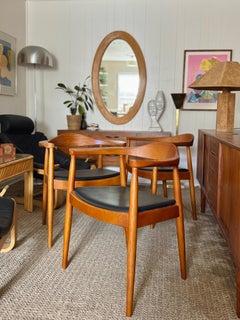 Iconic solid teak chairs with black leather seats in the style of Hans Wegner