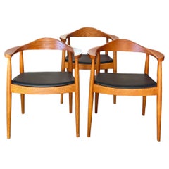 Iconic solid teak chairs with black leather seats in the style of Hans Wegner