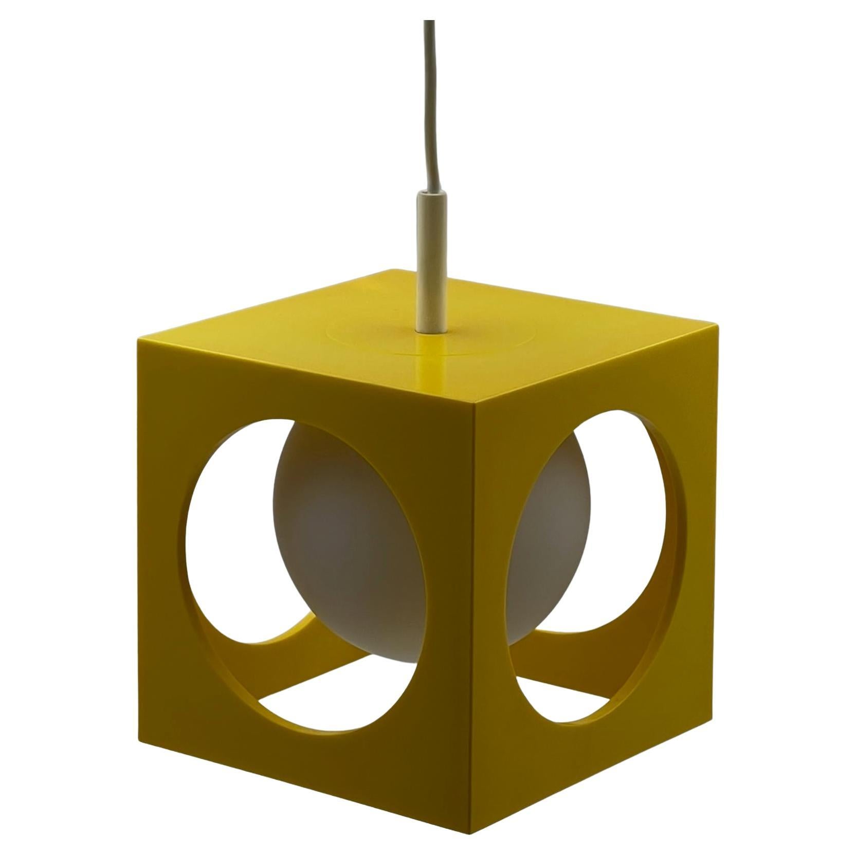 Illuminez votre espace avec cette étonnante lampe de l'ère spatiale conçue par Richard AGE Besigheimer. Cette suspension unique se compose d'un cube en plastique jaune brillant aux trous arrondis, abritant parfaitement une sphère de verre blanc