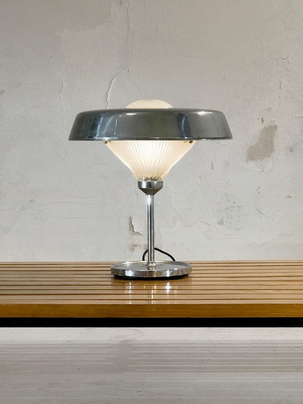 An iconic table lamp, Minimalist, Modernist, Space-Age, structure in chrome-plated metal, thick glass with geometric reliefs, encircled with an aerial lampshade Saturn-ring-like, by BBPR, original edition Artemide, Italy 1970.

A second same model