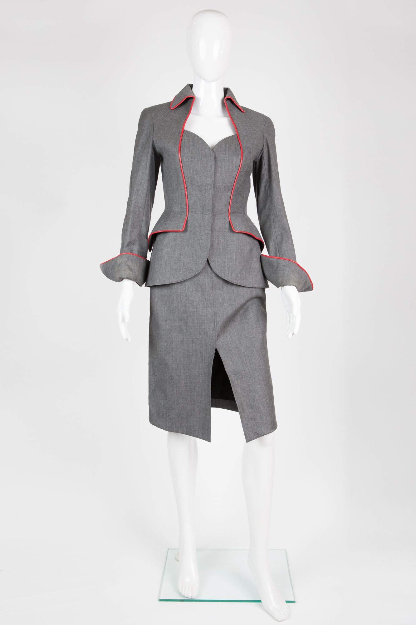 Thierry Mugler Couture grey and red suit featuring an iconic fitted jacket with shoulder pads, front snaps buttons, red leather piping details, fancy cuffs details, a red lining, and a fitted pencil skirt with front pockets, a waistband detail, a