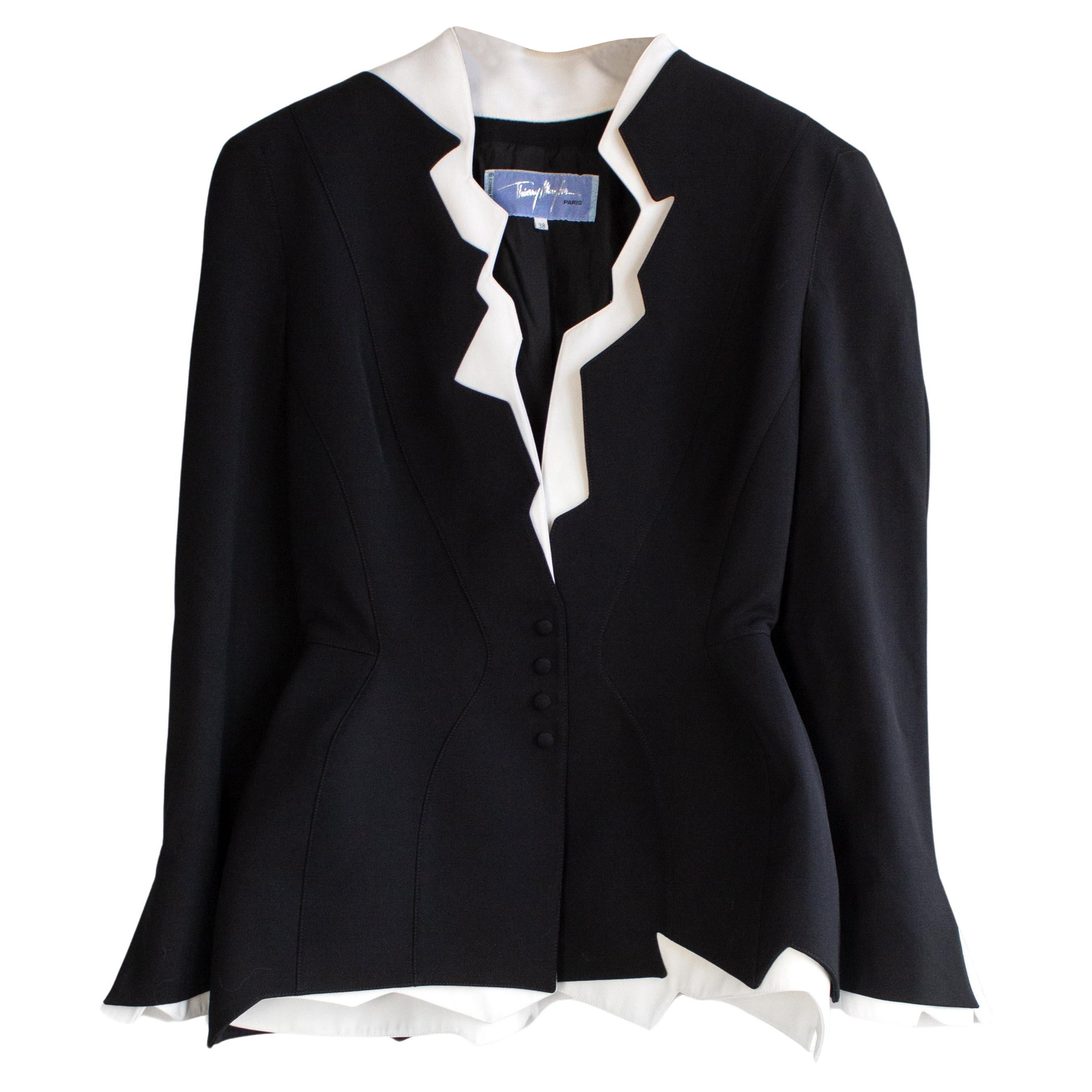 Questa eccezionale giacca bianca e nera è un capolavoro realizzato dal visionario Manfred Thierry Mugler per la sua collezione Primavera/Estate 1994. Indossato da Eva Herzigova e Brandi Quinones, è entrato a far parte della celebre mostra 