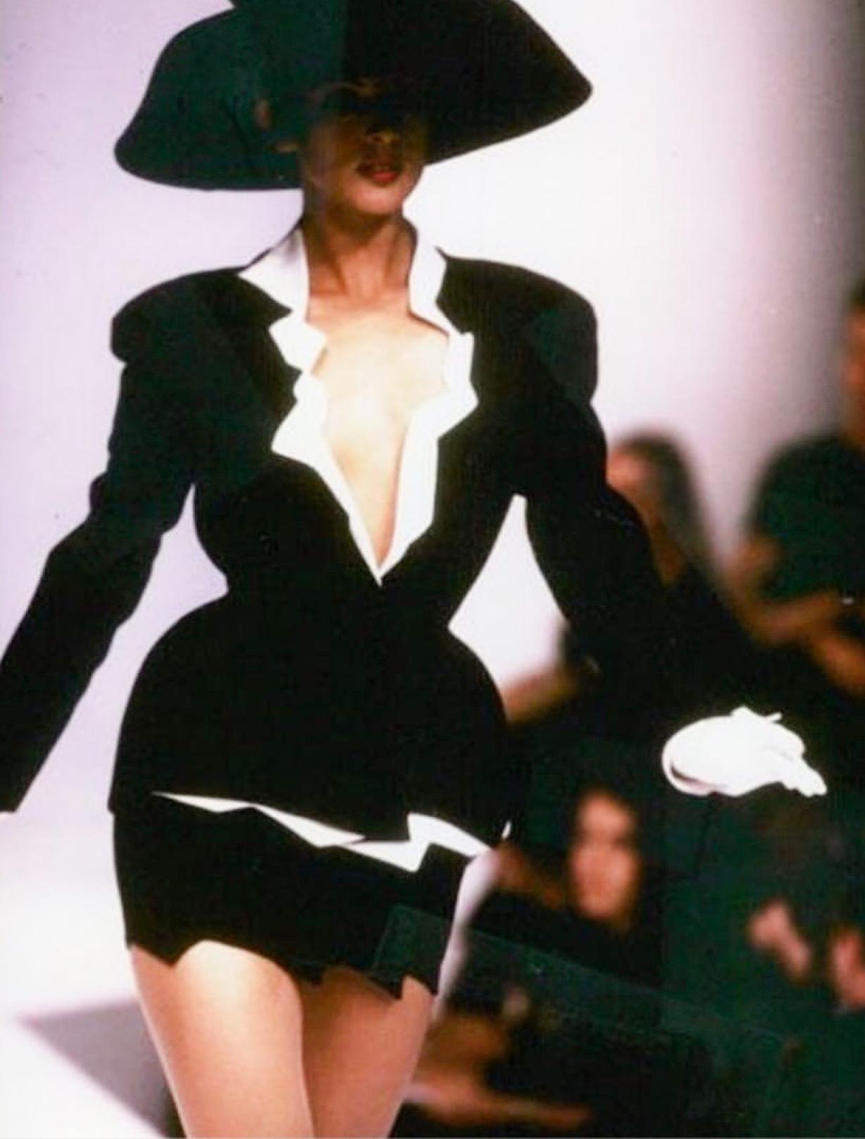 Cette exceptionnelle veste noire et blanche est un chef-d'œuvre réalisé par le visionnaire Manfred Thierry Mugler pour sa collection printemps-été 1994. Portée par Eva Herzigova et Brandi Quinones, elle a fait partie de la célèbre exposition