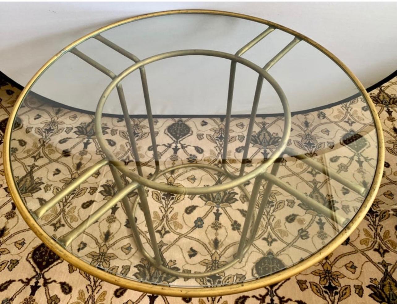 An iconic patio dining/bistro table in brass designed by Walter Lamb and produced by Brown Jordan. The round frame is supported by two concentric rings of brass with radial supports and a circular brass base. The round tabletop is a single piece of