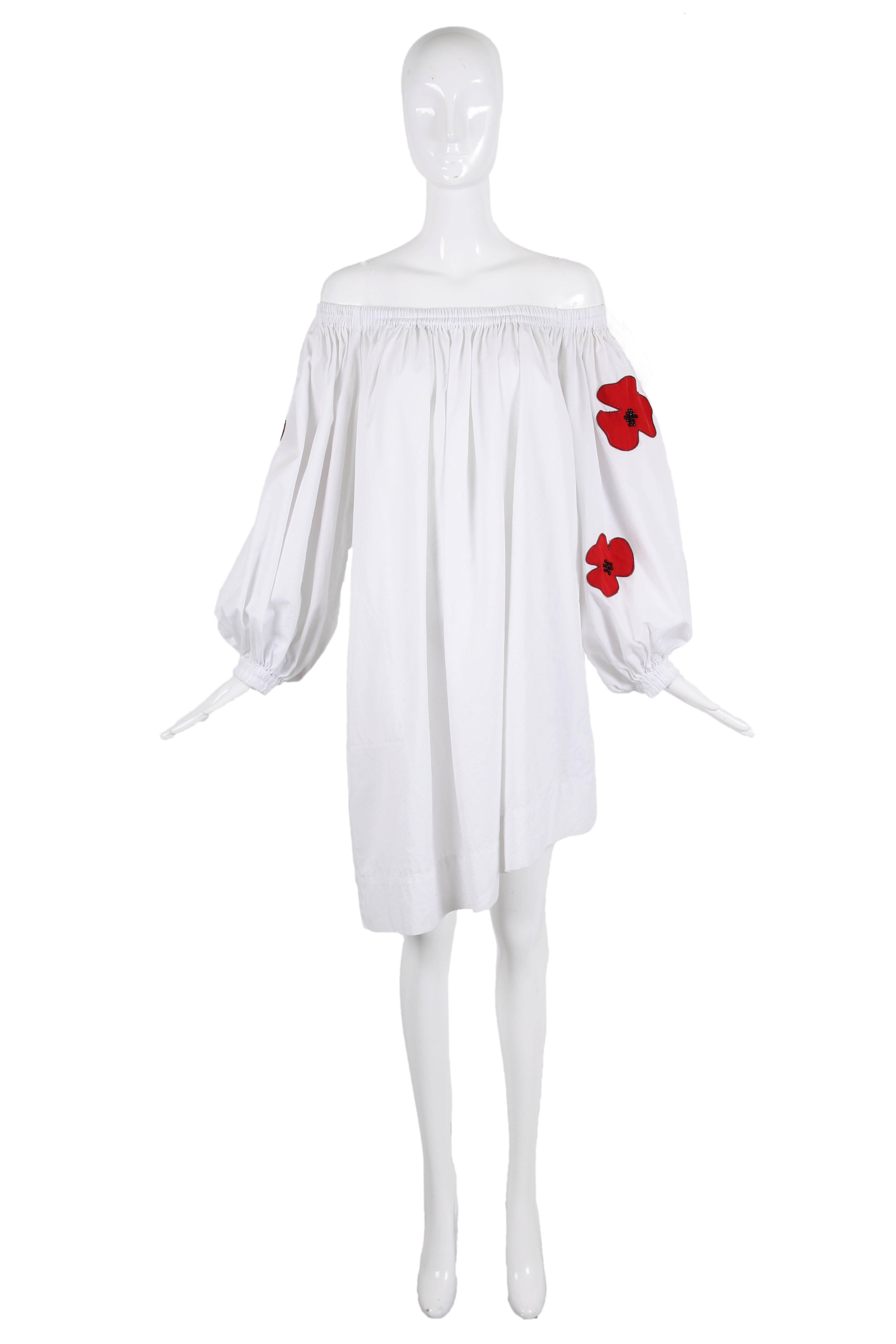 Yves Saint Laurent white cotton off the shoulder day dress with an asymmetric hem and poppy appliqués at sleeves. Features oversized 3/4 balloon sleeves with gathered elastic cuffs and hidden pockets at either side. In excellent condition/ Size tag