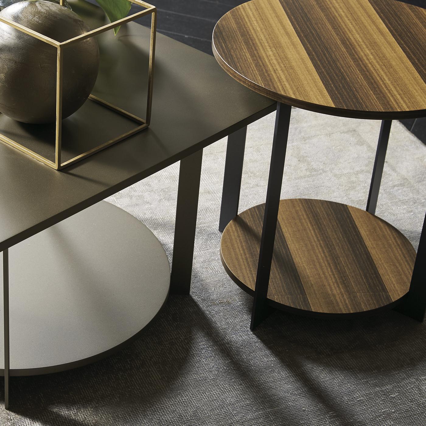 Part of a collection designed by Pierangeolo Sciuto, this side table is refined and modern and can be used in the living room, as well as in a study or bedroom. Its wooden structure has two ovals supported by a four-leg vertical structure. The metal