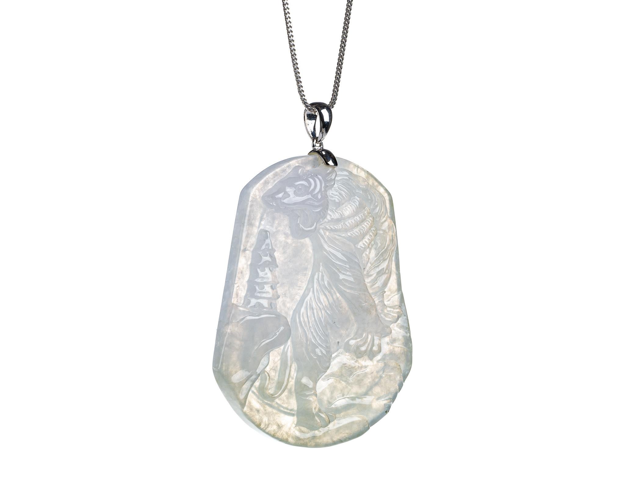 This is an all natural, untreated jadeite jade carved tiger pendant set on an 18K white gold bail.  The carved tiger symbolizes power, courage and strength.
   
It measures 1.89 inches (48mm) x 2.14 inches (54.5mm) with thickness of 0.27 inches