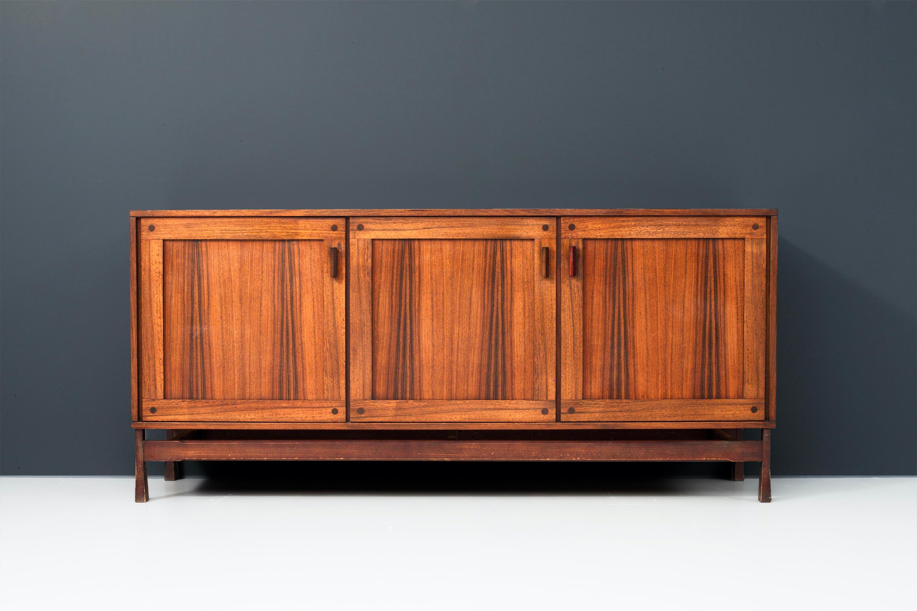 This sturdy three-door Italian credenza is in very good condition and has well balanced proportions. The wood of the top, doors and sides have dark, dynamic, almost dancing flames.
The door handles and drawer openings are geometrical shaped and
