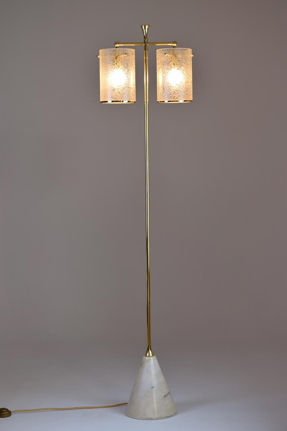 The Ido-F5 floor lamp is composed of givré glass cylinder shades with delicate brass rims. The double shade light is available in different shades: glass, wicker or fabric. The marble base can be colored in green or white.

2x60 W Max E14
230 V -