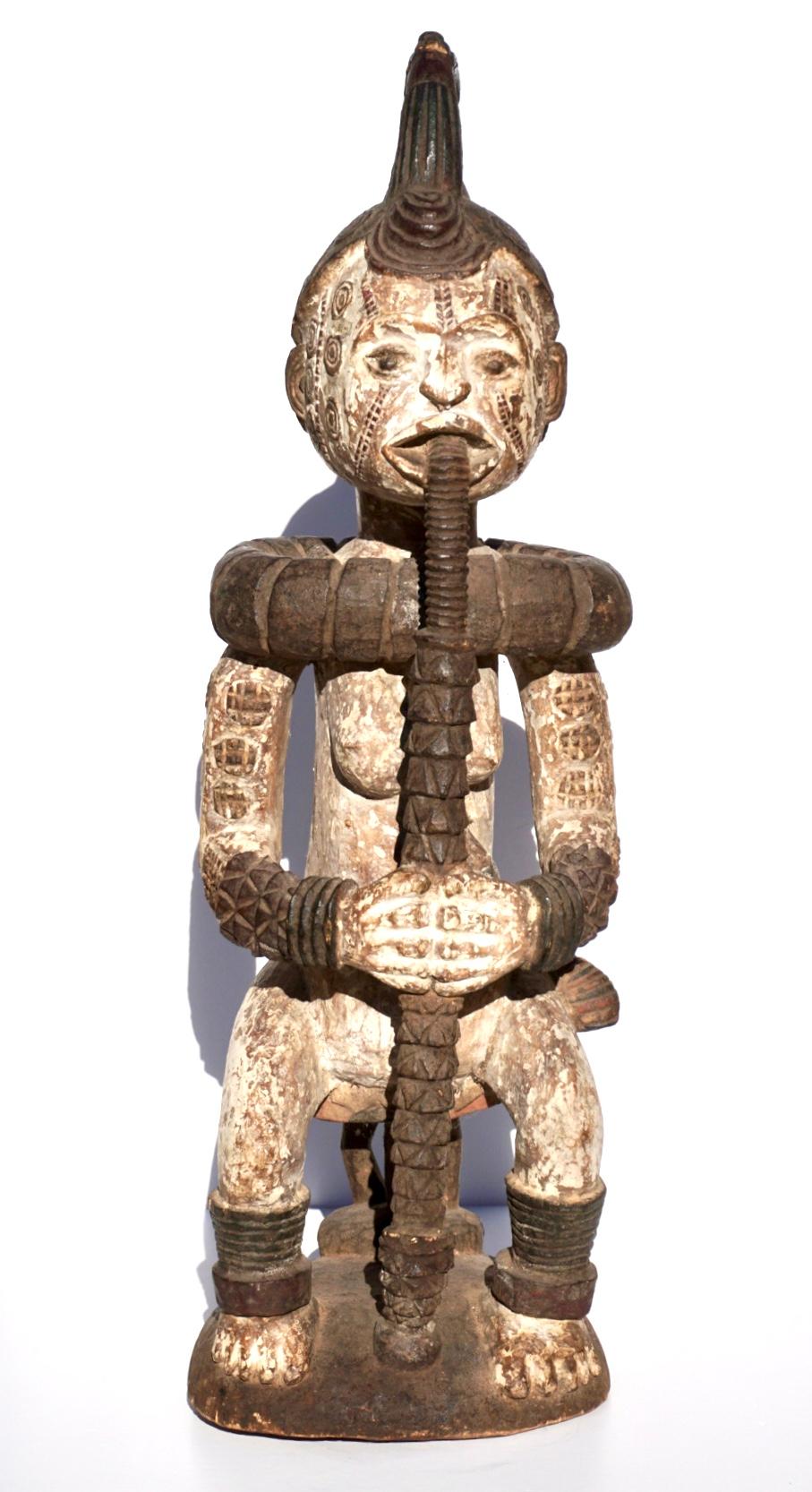 Idoma Ibo Weibliche Figur. Afrika, Nigeria 20. Jahrhundert oder früher.

Eine sitzende weibliche Figur auf einem Hocker, die eine lange Pfeife raucht, mit Pigmenten bemalt und mit Skarifikationen verziert, in stolzer Pose. Der helle Körper ist mit