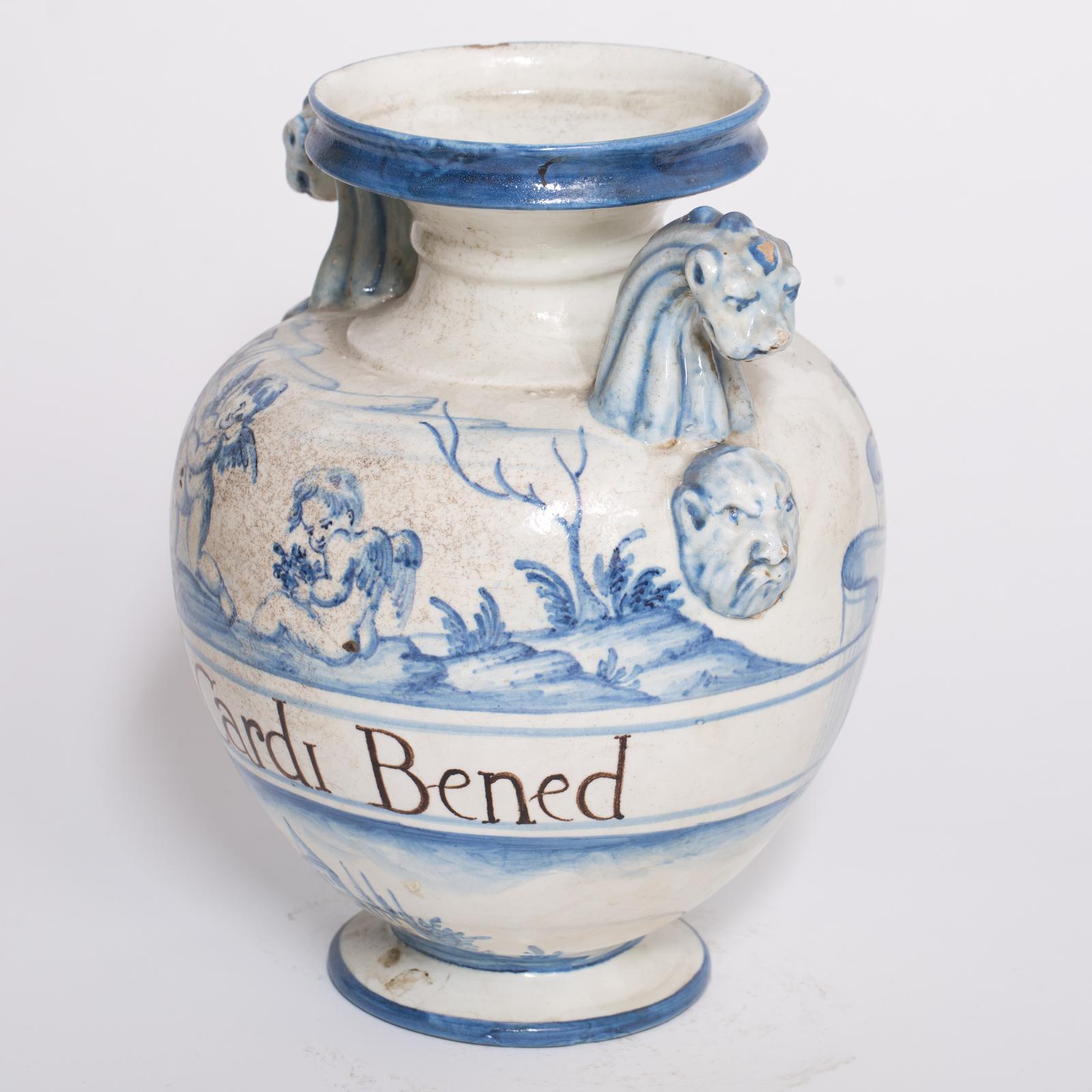 This vase is a reproduction of an antique apothecary jar, masterfully reproduced by the expert maiolica artisans of Manetti e Masini in Florence. Executed in blue and white Ligurian style, the maiolica piece features the writing of the content 