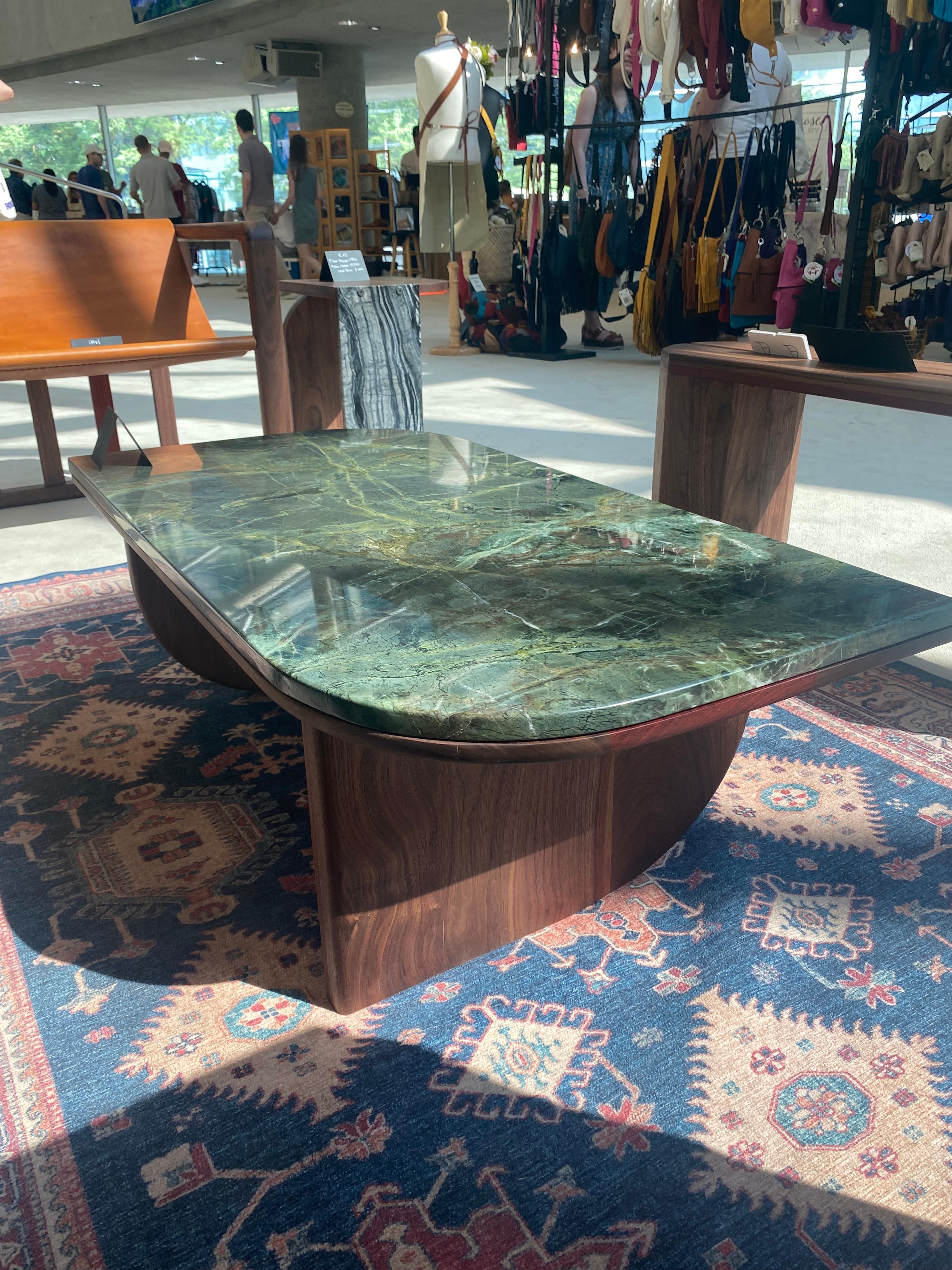 Voici notre exquise table basse en marbre et noyer, un mélange magistral de luxe et d'élégance naturelle. Cette pièce présente un plateau en marbre vert qui repose gracieusement sur une base robuste en noyer massif. Les teintes riches et naturelles