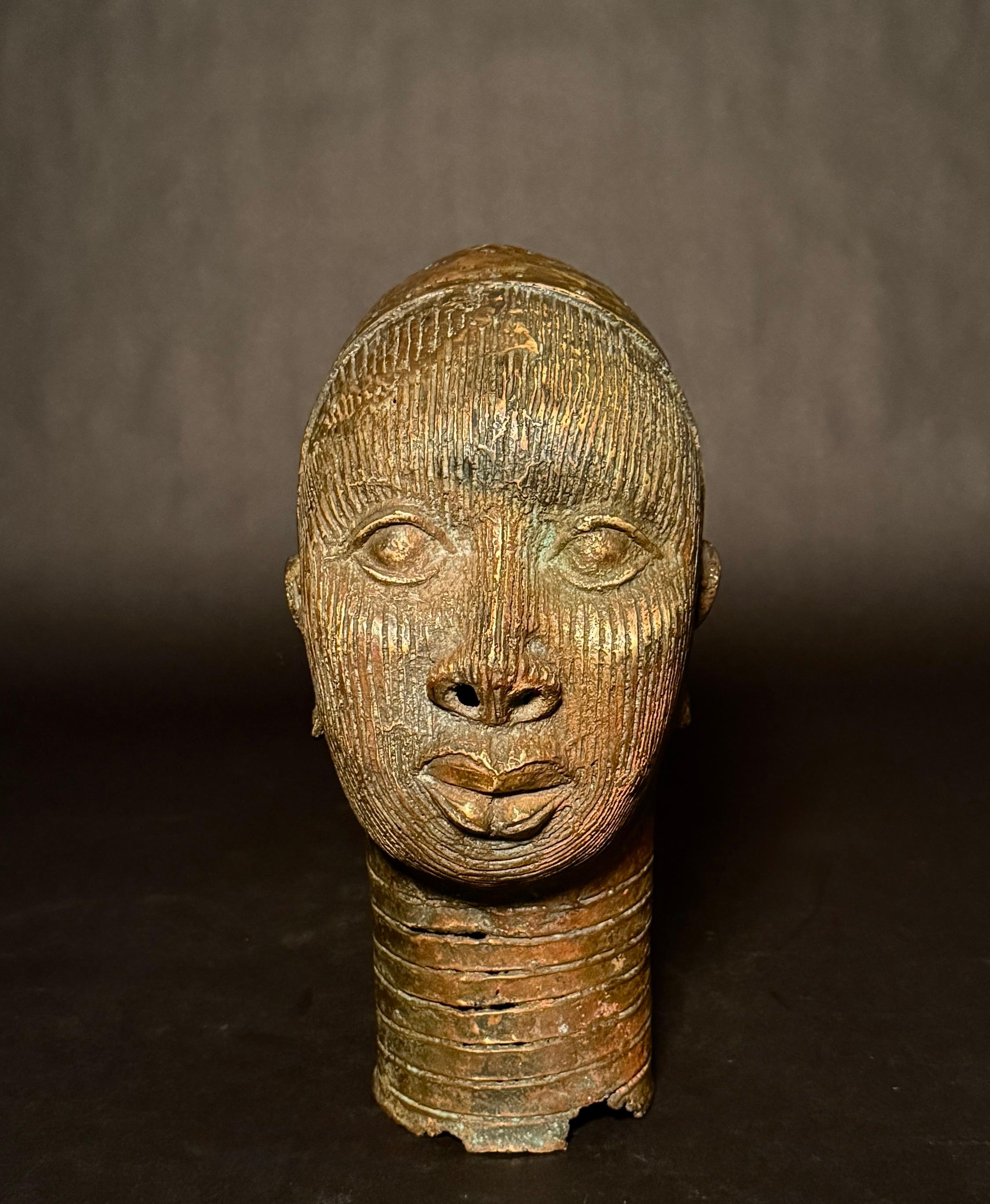 A finely cast bronze portrait head in the style of the ancient Yoruba kingdom of Ife, Nigeria. This dignified bust exhibits hallmark features of classical Ife art, including elegant vertical facial striations, delicately modeled lips, almond-shaped