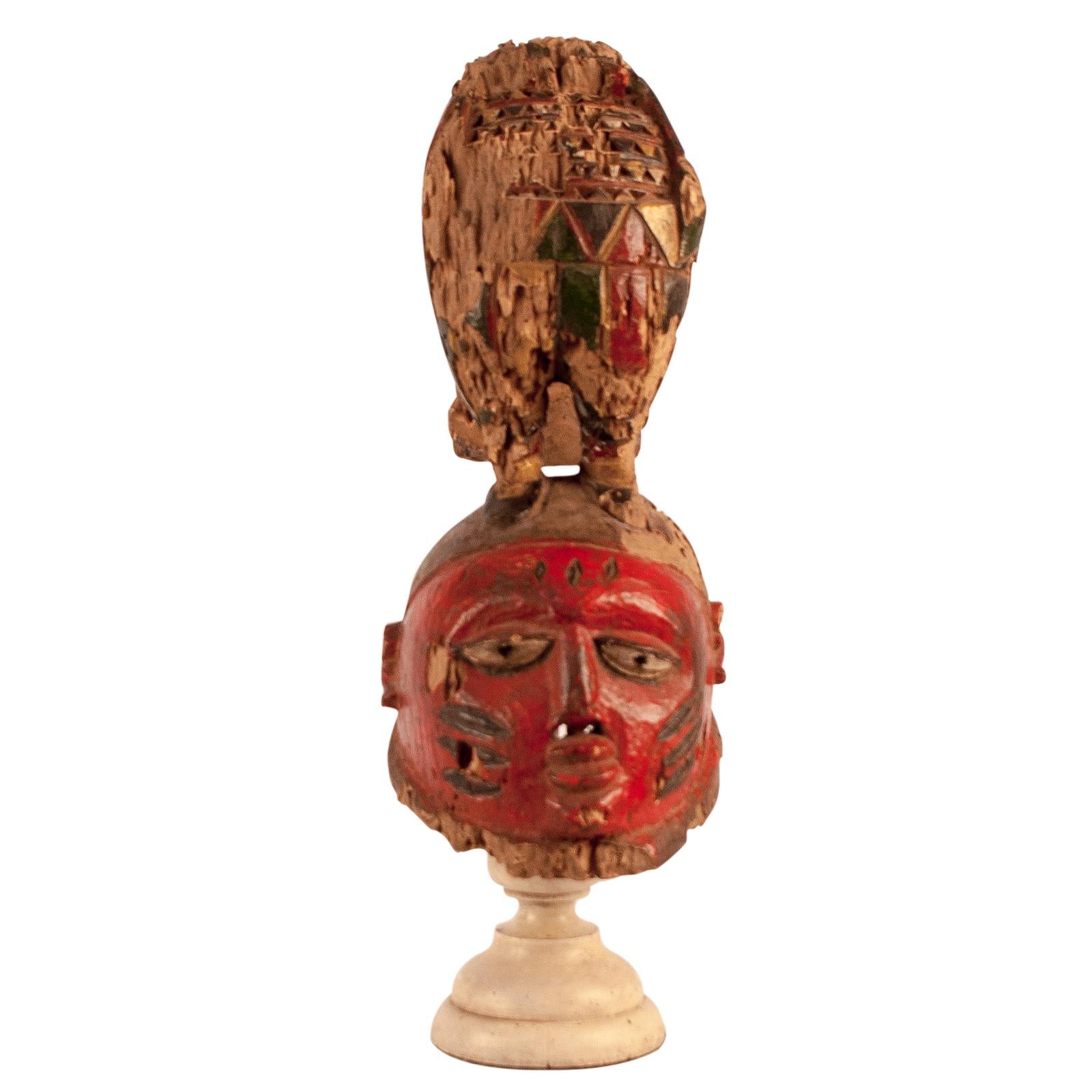 A 19th century Nigerian Igbo dance mask on a later stand. Paint refreshed in the early 20th century. This mask shows extensive inactive insect trails. It is also probable that they painted this several times. This was worn on the top of the head