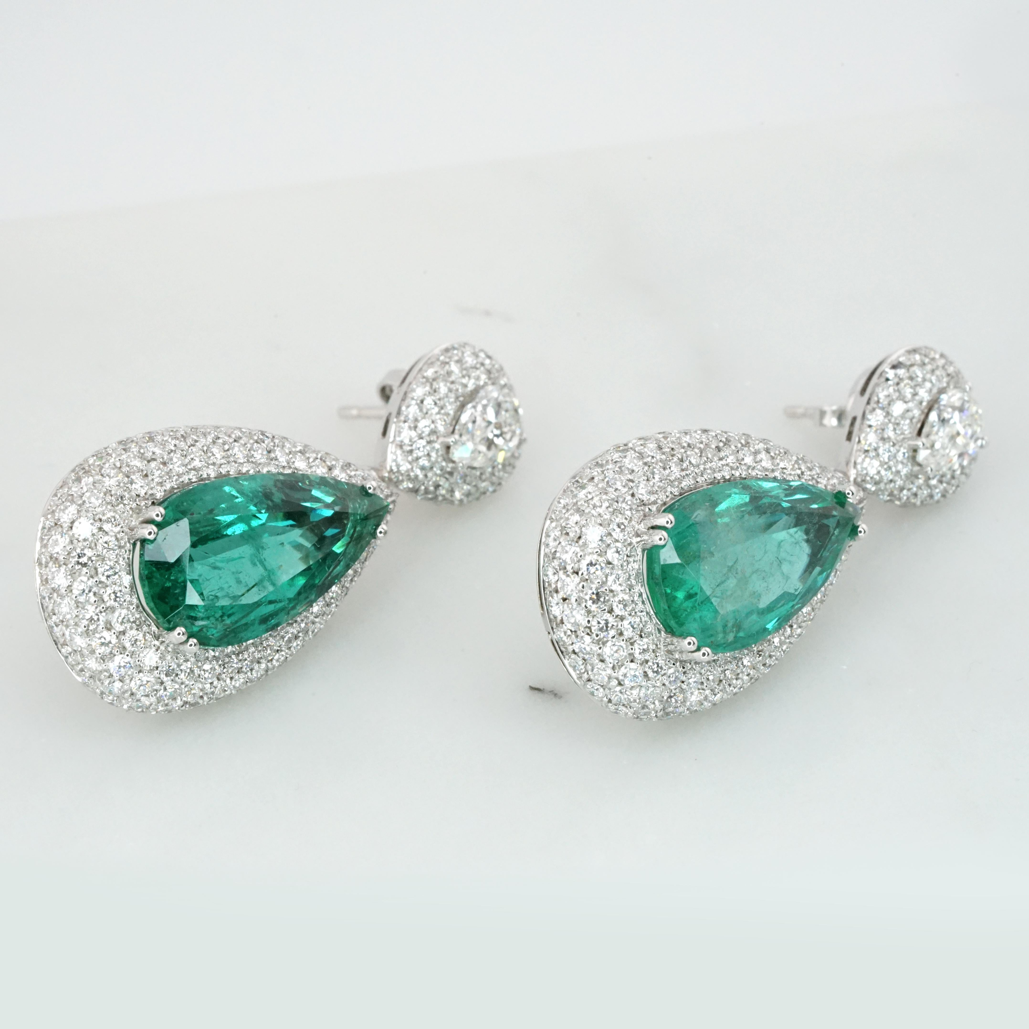 Exuding elegance and timeless sophistication, these earrings feature a stunning pair of IGI certified pear cut green emeralds, weighing approximately 13 carats in total. These exquisite emeralds are the centerpiece of the design, displaying a vivid