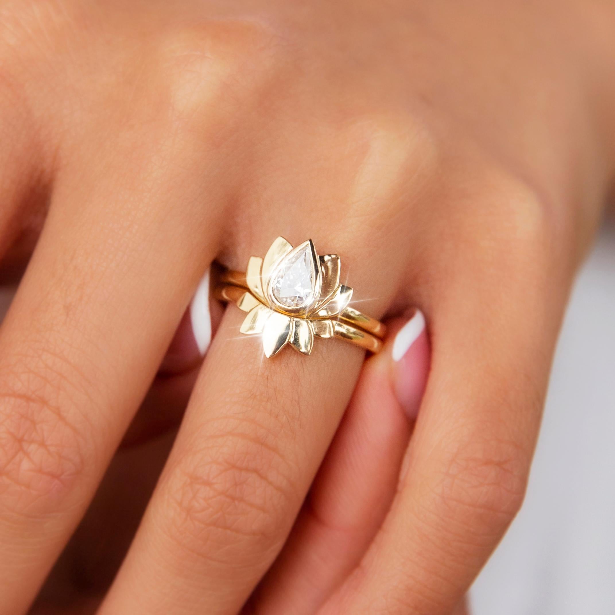 Forged in 18 carat yellow gold, this darling contemporary engagement ring set features a graceful lotus flower holding a certified 0.52 carat pear brilliant cut diamond. This gorgeous two piece set is named The Takeshi Ring. She is a wonderful