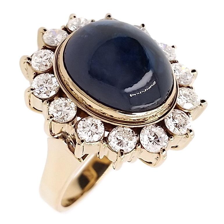 Adorn yourself with this captivating ring, boasting a magnificent 12.10ct Natural Not-Treated Sapphire paired with 1.73ct Natural Diamonds. The allure of the oval cabochon sapphire, with its intense blue hue and transparent clarity, is enhanced by
