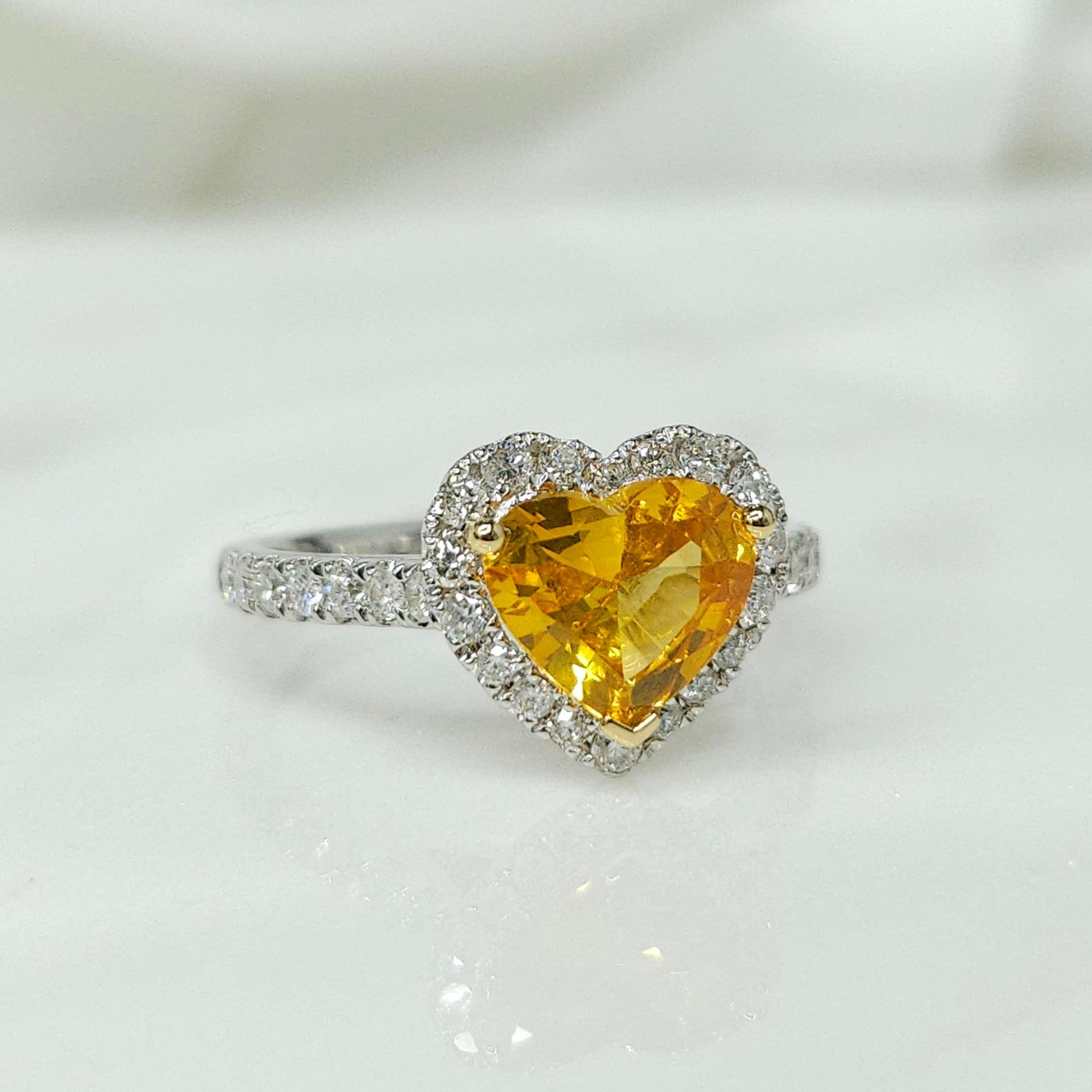 Prepare to be captivated by the exquisite IGI certified 18K white gold 1.29ct heart-shaped Yellow Sapphire (vivid orangy yellow) and 0.41ct diamond ring, a true masterpiece of fine jewelry design.

At the center of this stunning ring is a