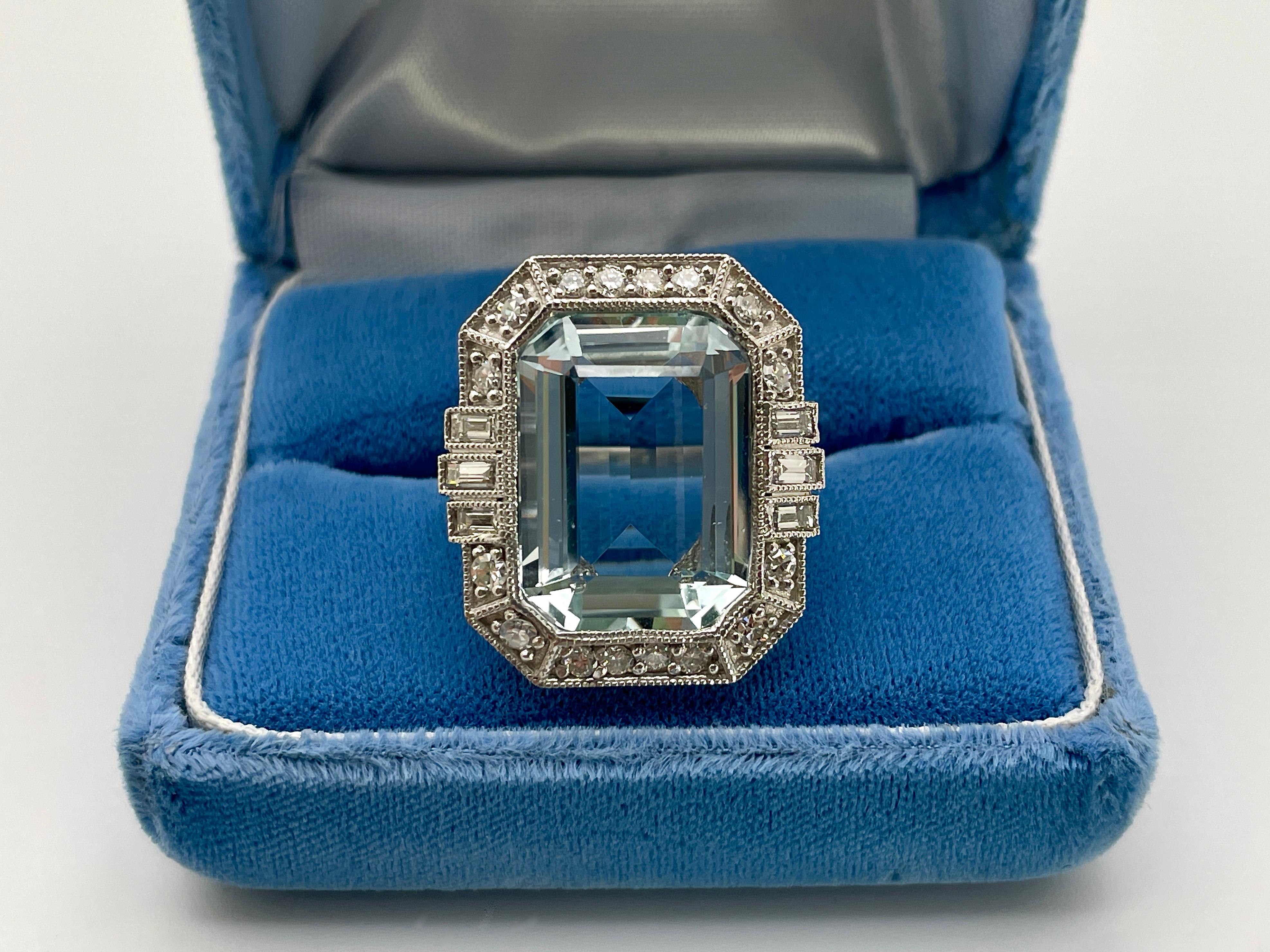 This exquisite hand-crafted platinum aquamarine ring features a breathtaking IGI Certified 12.97 carat emerald-cut natural beryl aquamarine, measuring 18.15 x 13.18 x 7.42 mm. The aquamarine showcases a stunning pale summer sky blue hue, radiating