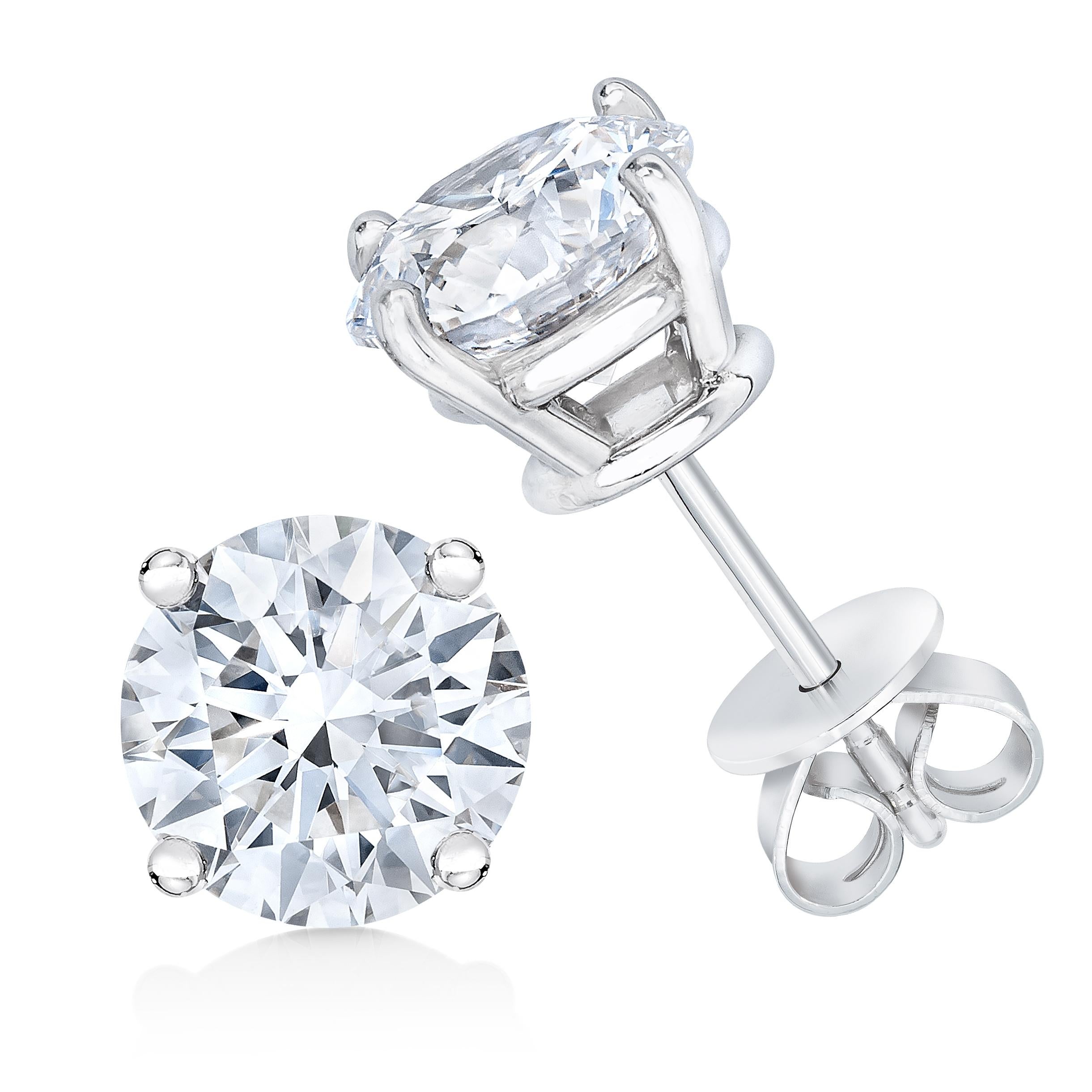 Paire de boucles d'oreilles classiques en diamant solitaire, chacune ornée d'un diamant rond de taille brillant serti dans un panier en or blanc 14 carats à quatre griffes. Ces boucles d'oreilles certifiées IGI ont un poids total de diamants de 1