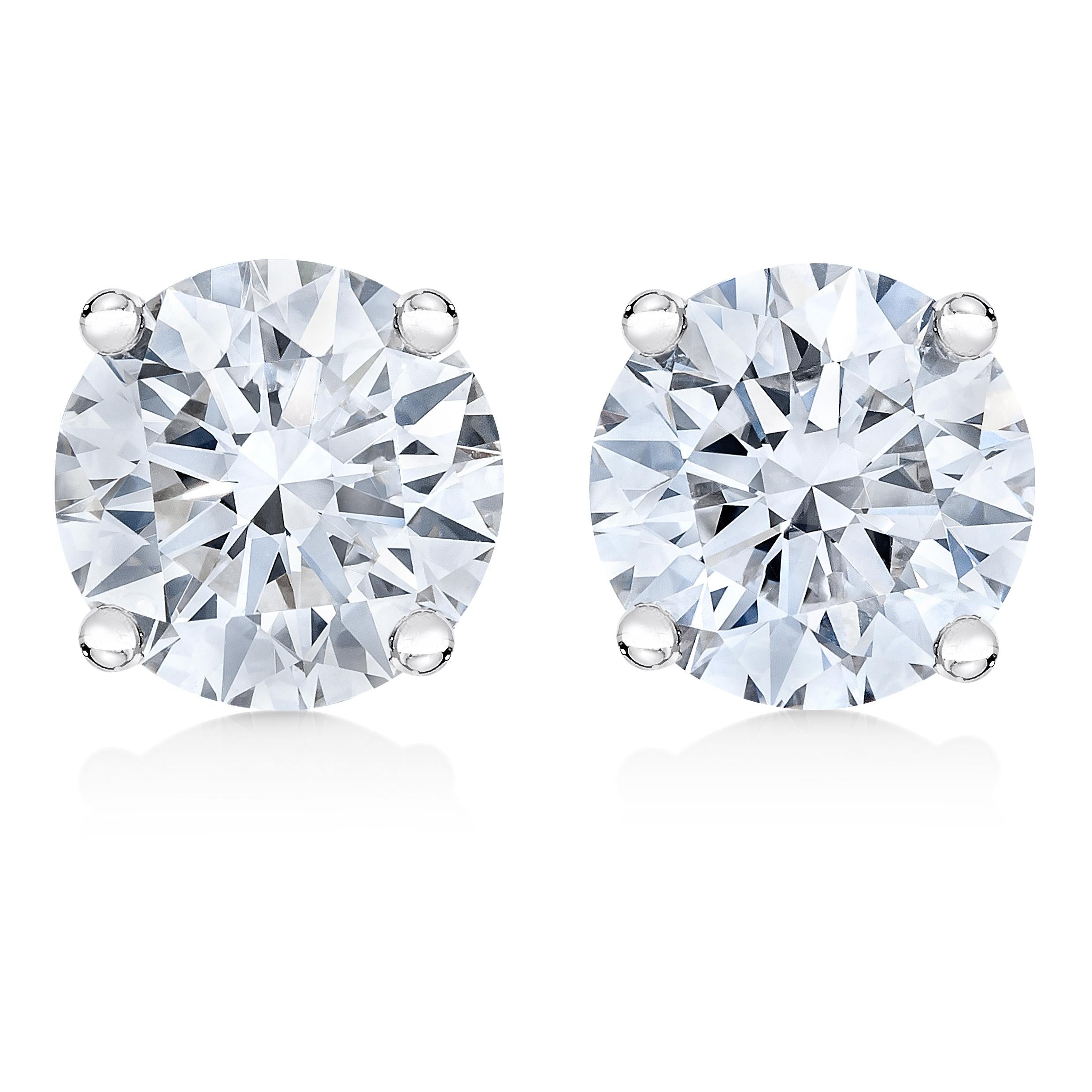 Un clásico par de pendientes de diamantes solitarios, cada uno con un único diamante redondo de talla brillante engastado en una cesta de 4 garras de oro blanco de 14 quilates. Estos pendientes con certificado IGI tienen postes de fricción y cierre