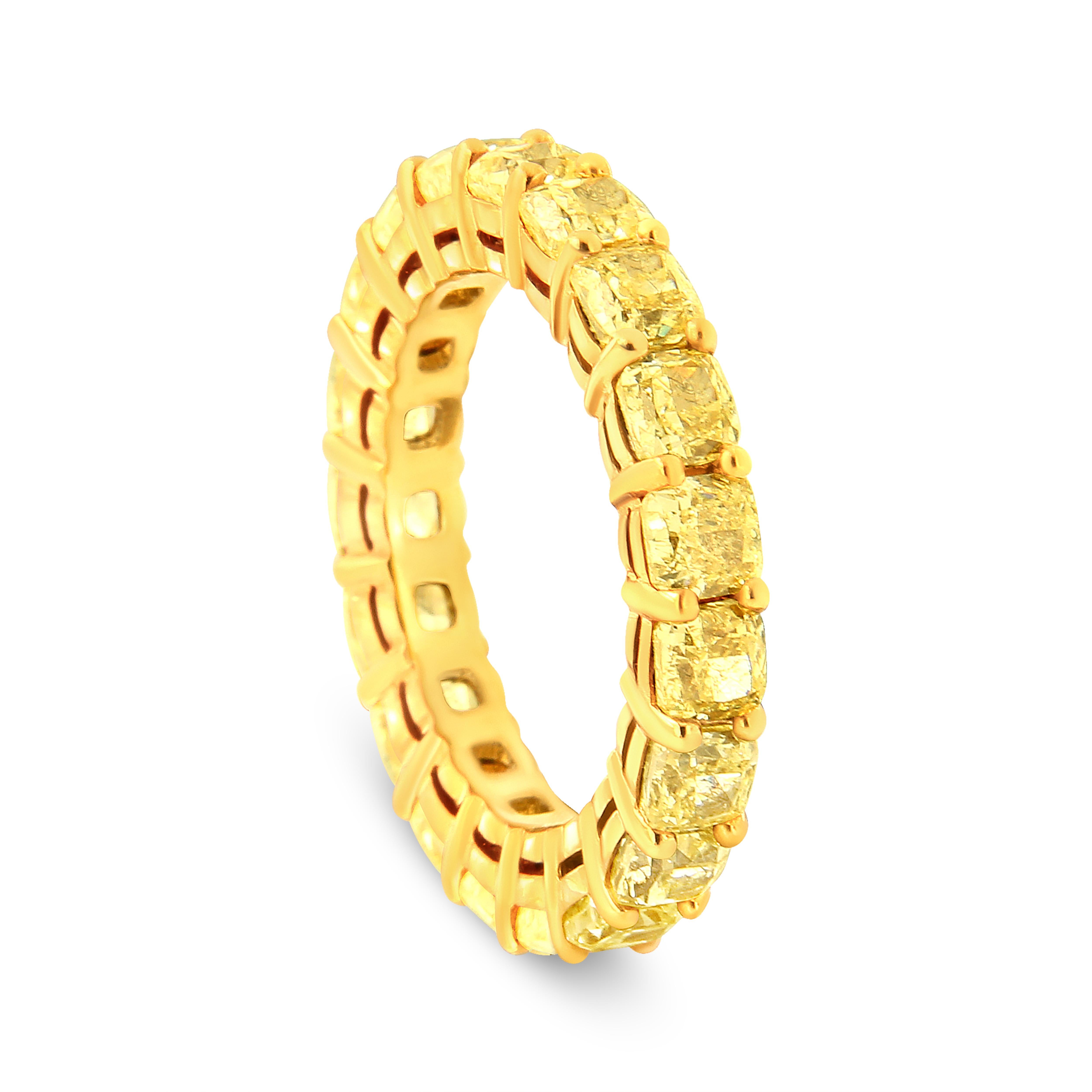 This band is crafted from 18-karat yellow gold and has a stunning 5.0 cttw of natural, yellow cushion diamonds. This magnificent diamond eternity band features beautifully matched 19 cushion cut yellow diamonds in a shared prong setting. The total