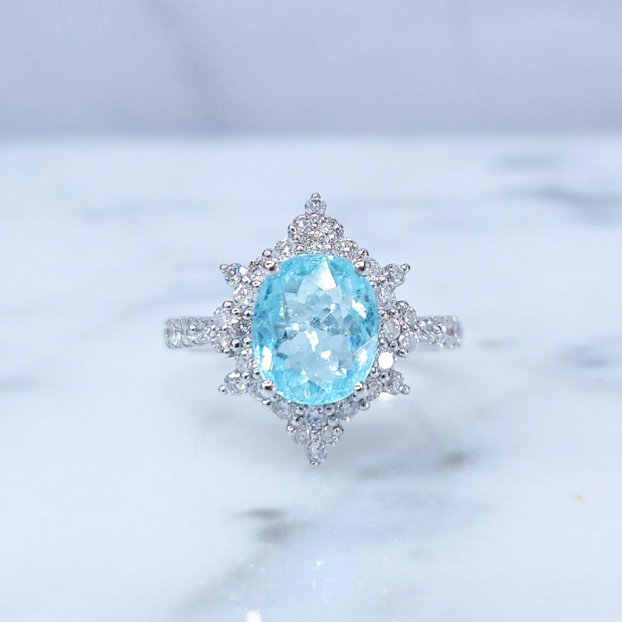 This exquisite ring features a captivating 2.13-carat oval-shaped Paraiba tourmaline, a rare and highly sought-after gemstone known for its intense neon blue-green color. The tourmaline is set in a classic four-prong setting, allowing its vibrant