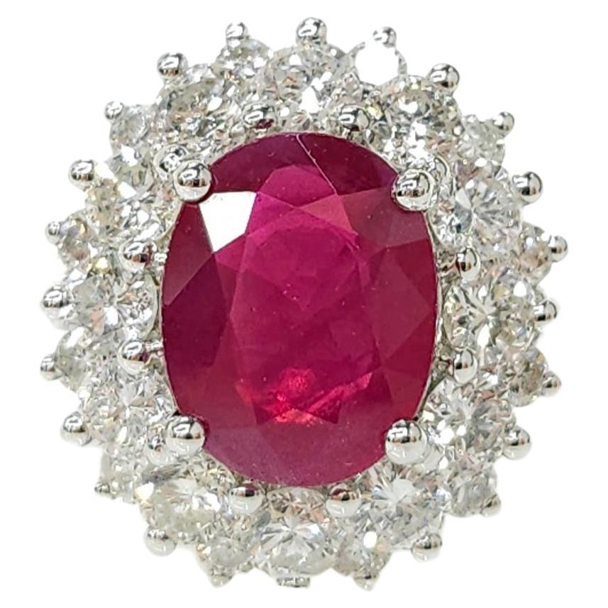 Indulge in the mesmerizing allure of this luxurious IGI Certified 2.40 Carat Ruby and Diamond Cluster Ring, a stunning piece crafted in elegant 18K white gold. The centerpiece of this exquisite ring is a captivating 2.40 carat oval-shaped ruby,