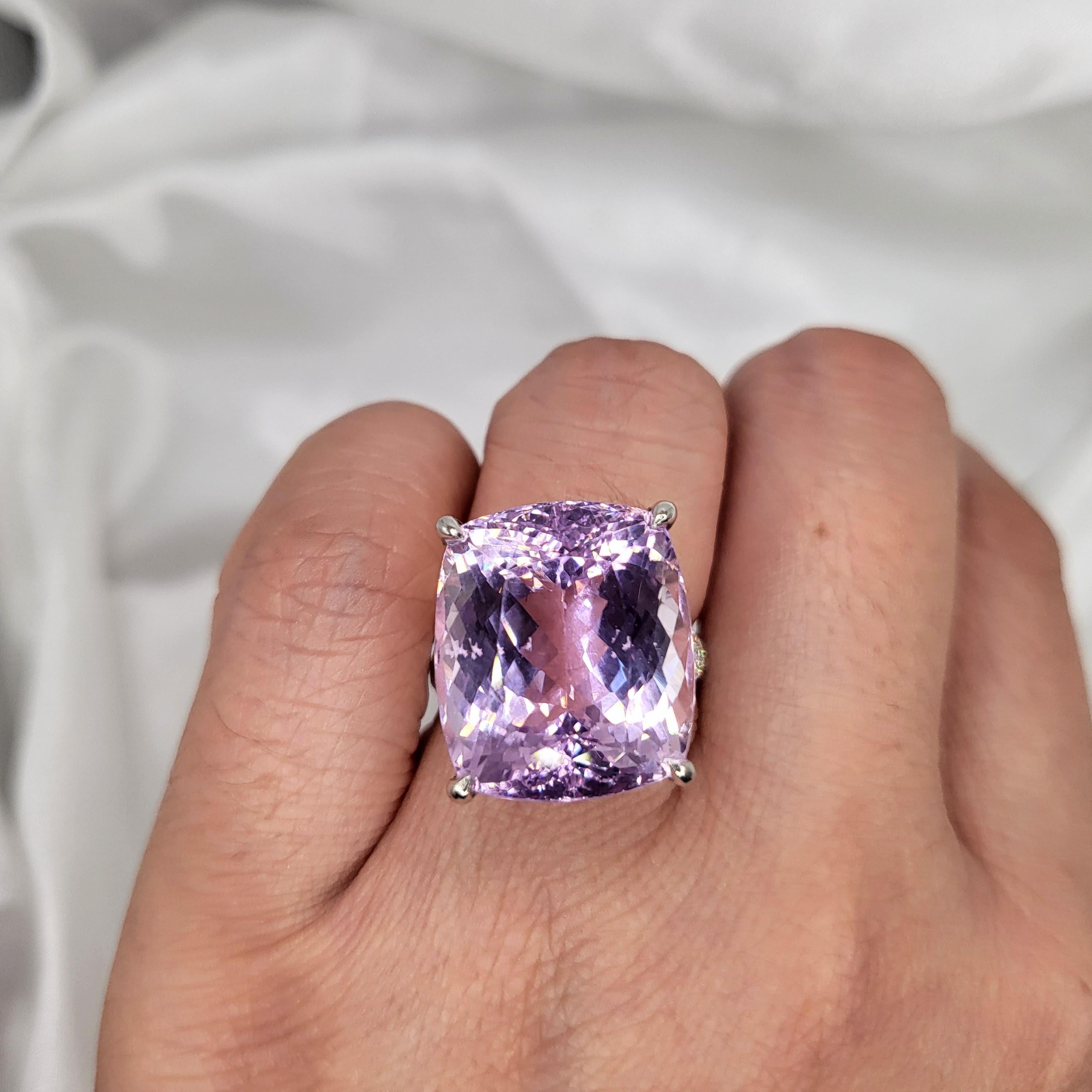 Cette magnifique bague de cocktail présente une Kunzite certifiée IGI de 24,20 carats de couleur rose violacé intense et de forme coussin, sertie dans de l'or blanc 18 carats. La pierre précieuse Kunzite vibrante est complétée par 30 diamants ronds