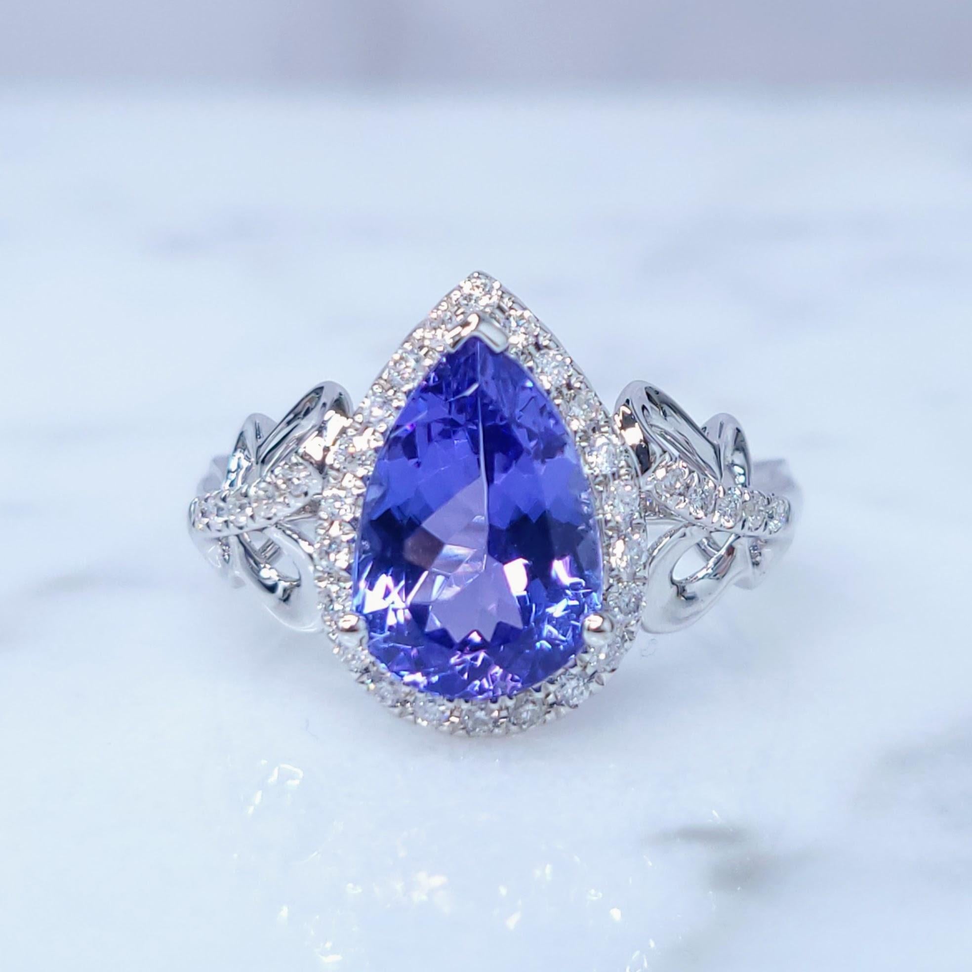 This exquisite ring features a stunning 2.47-carat pear-shaped Tanzanite, a gemstone renowned for its captivating blue-violet color. The Tanzanite is set in a classic three-prong setting, allowing its brilliance to shine.

Surrounding the Tanzanite