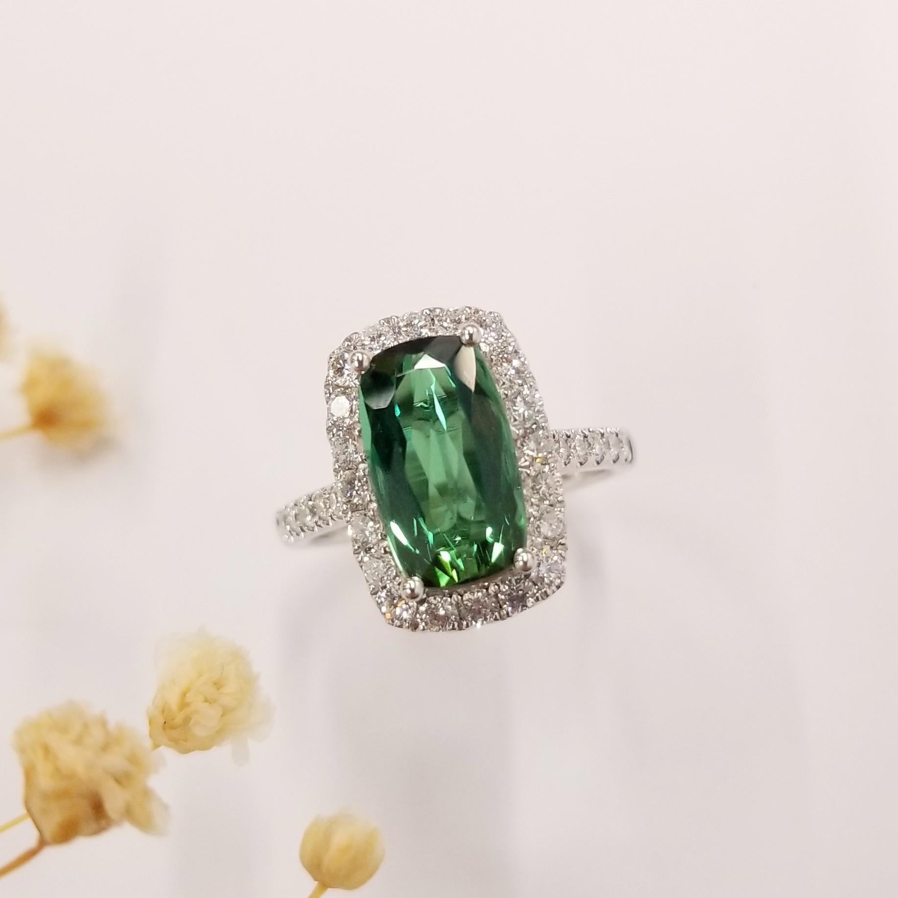 Introducing a magnificent piece of jewelry showcasing an IGI Certified 2.73 Carat Tourmaline in a mesmerizing intense green color. This rare gemstone, with an exceptionally long cushion shape, takes center stage in a modern style ring crafted from