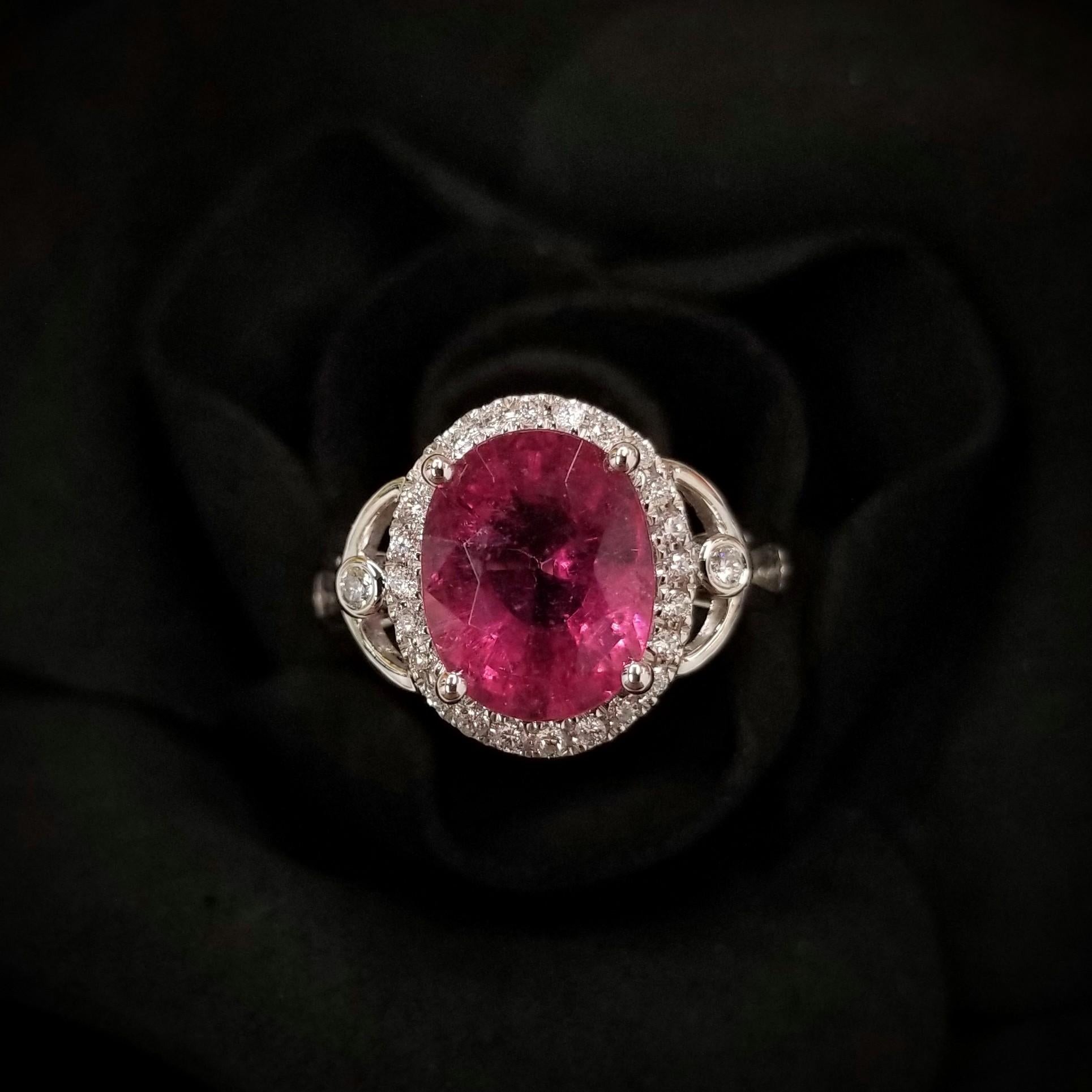 Introducing a breathtaking piece of jewelry featuring a dazzling IGI Certified 3.22 Carat Tourmaline in a striking vivid purplish pink color. The oval-shaped tourmaline takes center stage in this modern style ring crafted from 18K White Gold and is