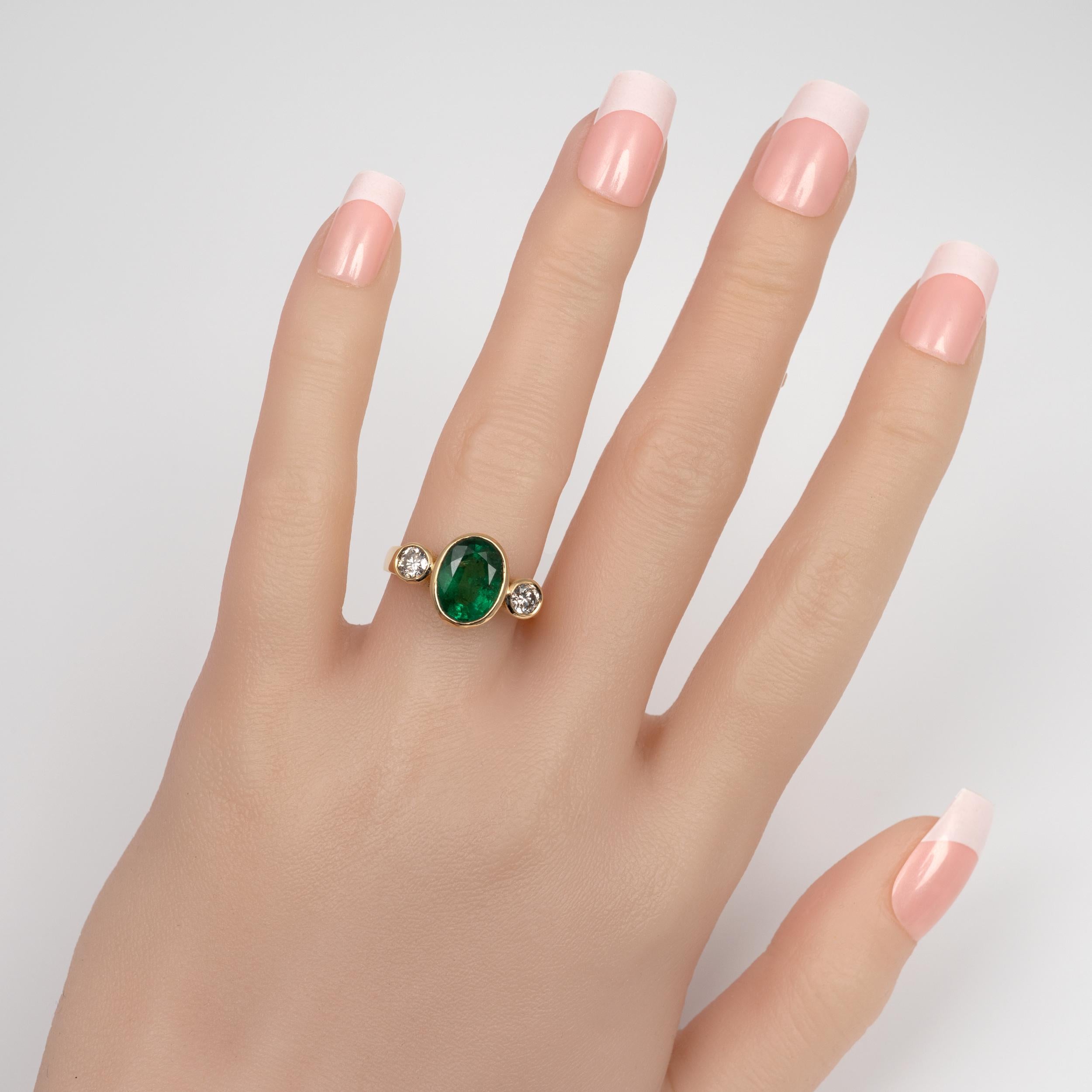 This superb emerald and diamond ring is beautifully crafted in 18 karat gold.

The ring is both striking and beautiful and features, in a classy bezel setting arrangement, a central oval cut 3.5-carat emerald gemstone is flanked by round-cut
