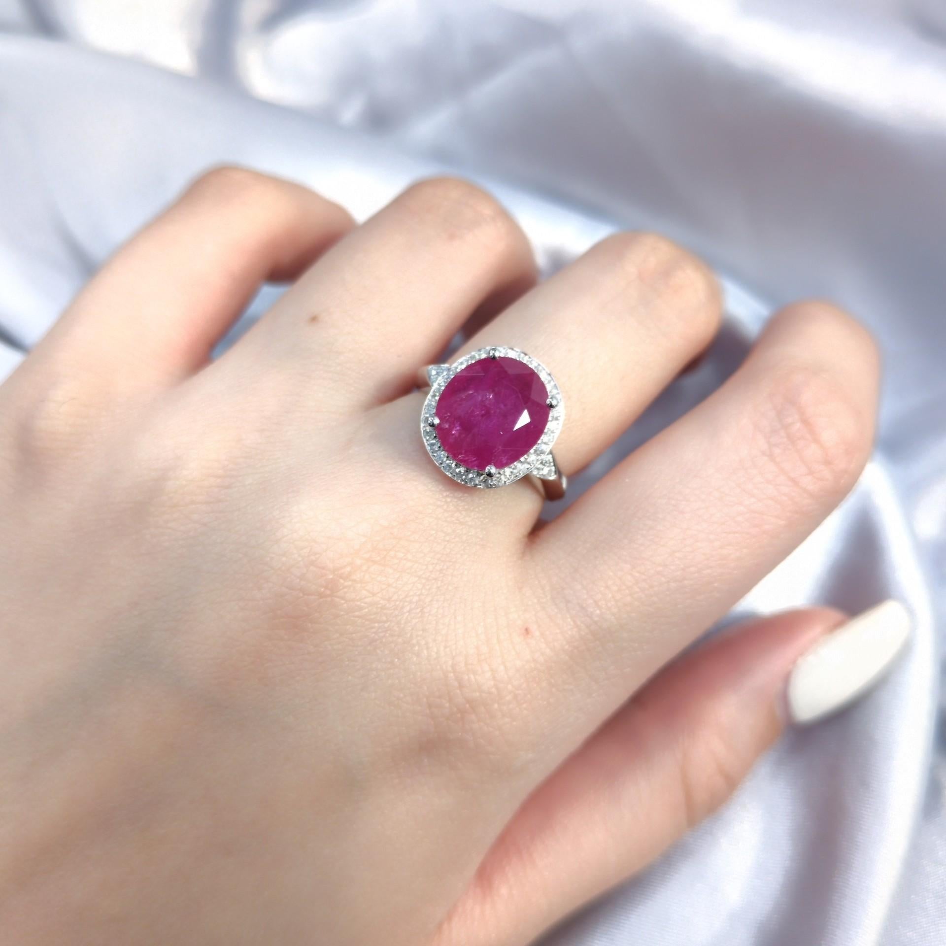 Imagine the captivating allure of this exquisite 18K white gold ring, a true masterpiece of elegance and vibrant color.  At its heart lies a breathtaking 3.82 carat oval mixed cut ruby, a gem that radiates passion and sophistication.  This isn't