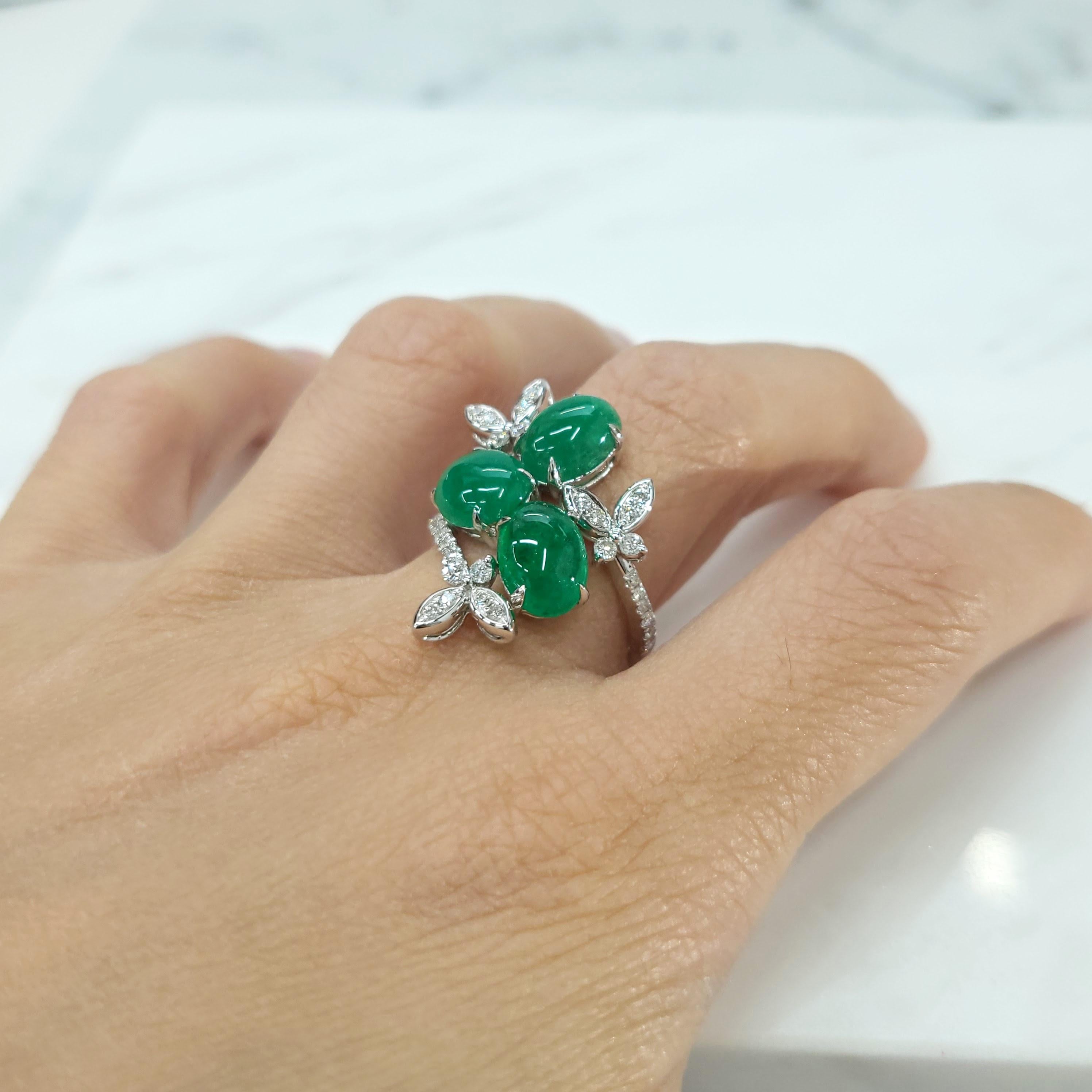 Der atemberaubende Ring aus IGI-zertifiziertem 18-karätigem Weißgold besticht durch drei Cabochon-Smaragde von insgesamt 4,43 Karat und 0,43 Karat funkelnde Diamanten. Dieser einzigartige Cocktailring ist ein wahres Zeugnis für Kunstfertigkeit und
