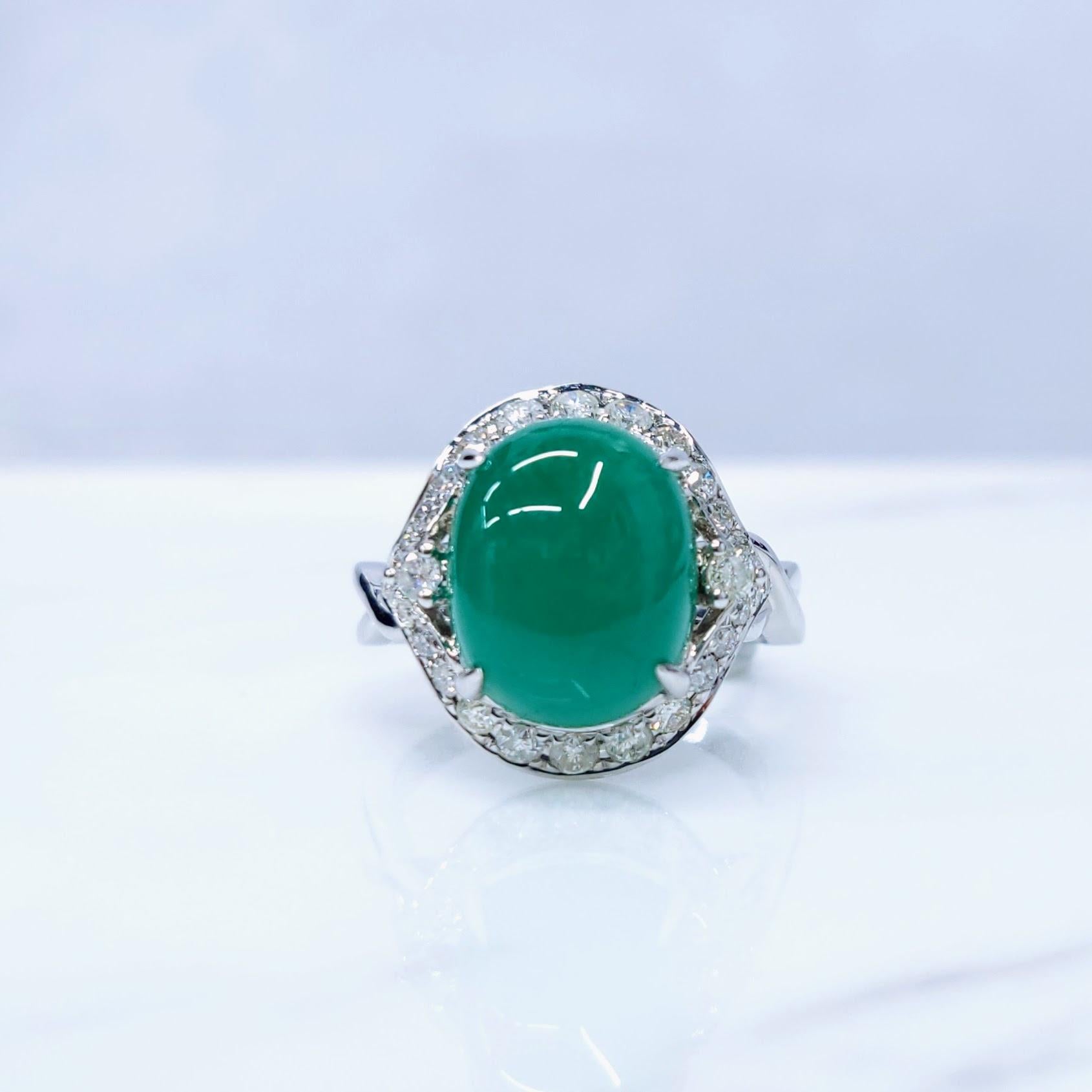This exquisite ring features a captivating oval-shaped cabochon Colombian emerald, weighing 4.85 carats. The emerald's rich green color, characteristic of Colombian emeralds, is complemented by a sparkling halo of diamonds, totaling 0.44 carats. The