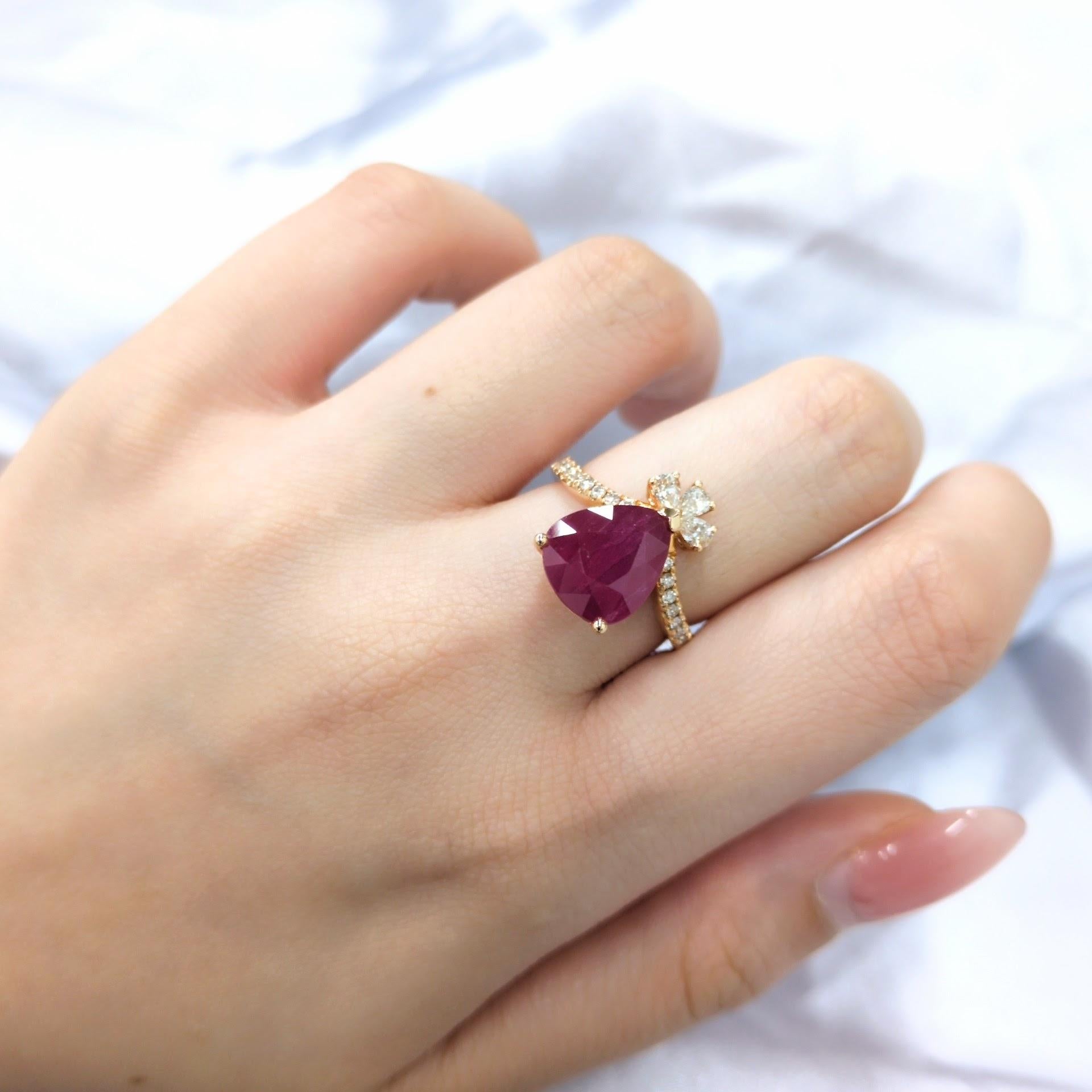 This exquisite ring showcases a stunning 5.13-carat pear-shaped Burmese ruby, a gemstone renowned for its intense red color and exceptional clarity. The ruby is set in a classic four-prong setting, allowing its brilliance to shine.

Above the ruby,