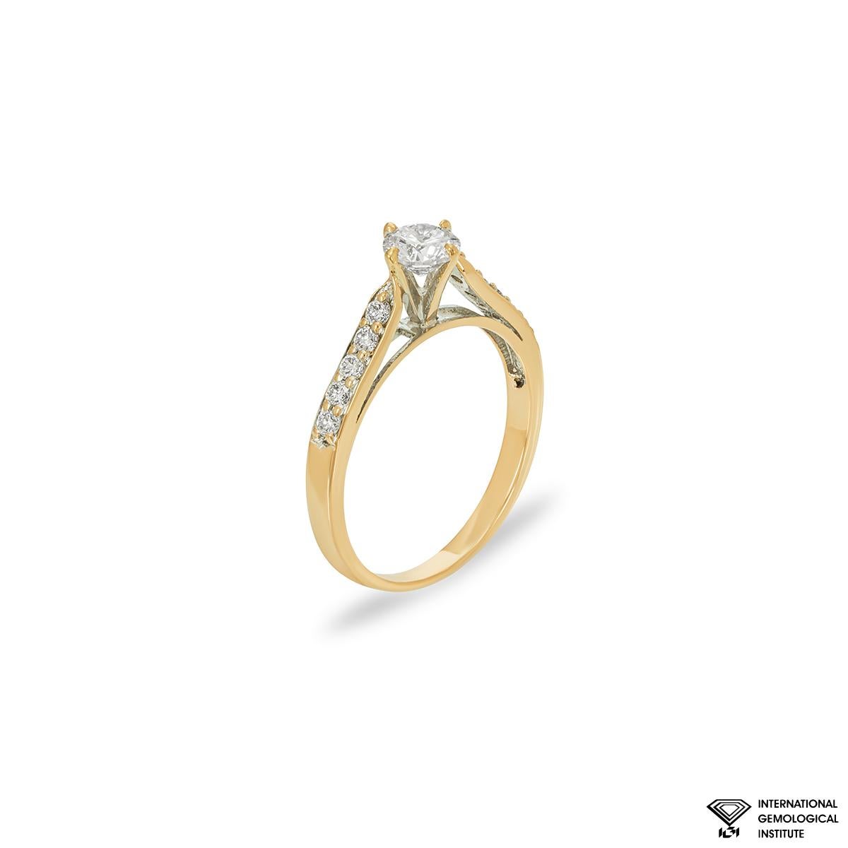 An alluring 18k yellow gold diamond engagement ring. The ring is set to the centre with a round brilliant cut diamond weighing 0.52ct, faint pink colour and SI2 clarity. The centre diamond is complemented by 10 round brilliant cut diamonds set to