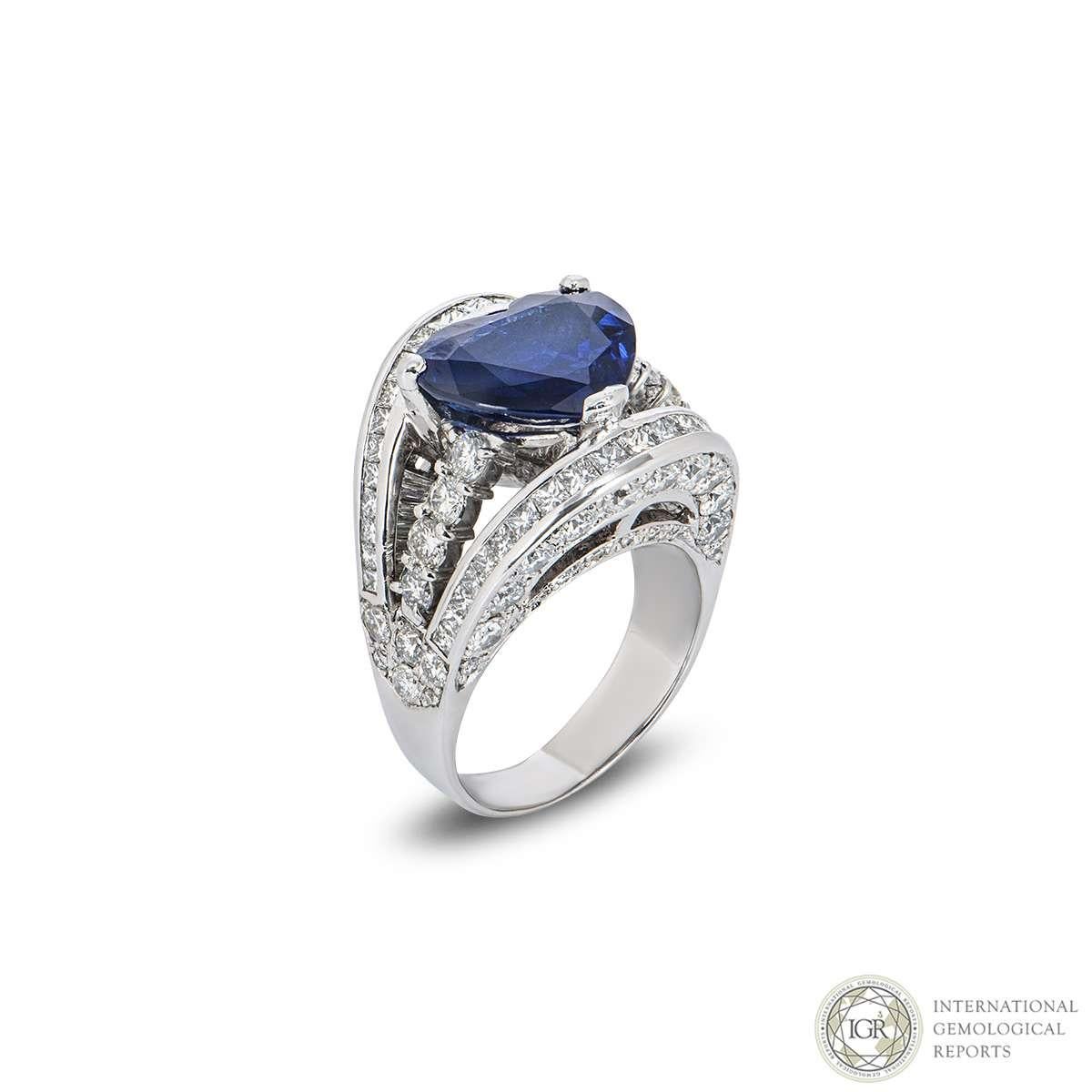 A statement 18k white gold diamond and sapphire dress ring. The ring comprises of a heart cut sapphire weighing 7.66ct, with a strong violetish blue hue throughout, type II VVS clarity. The sapphire is set between 3 bands which are diamond set with
