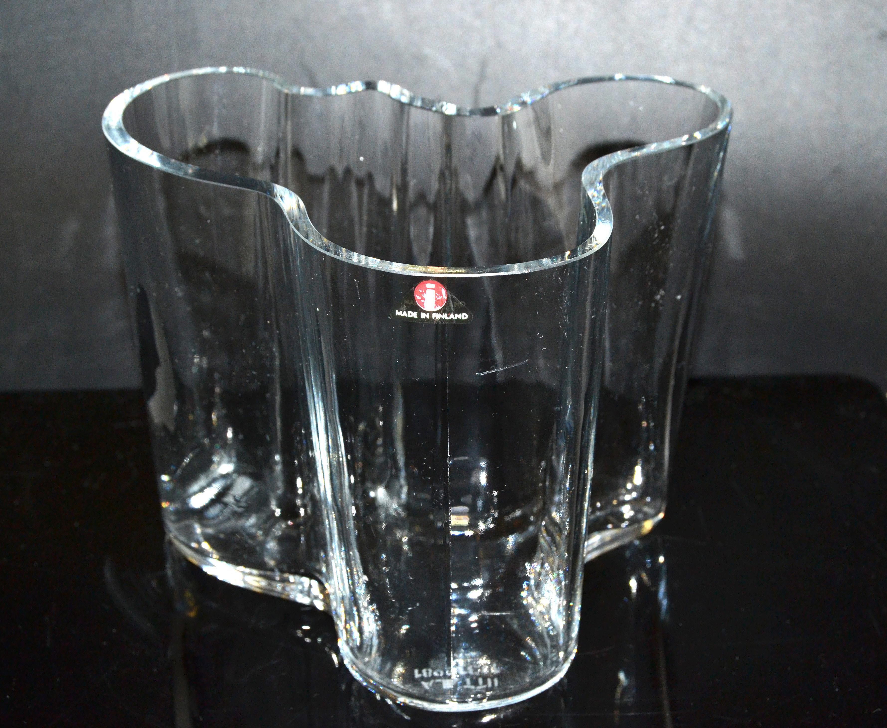 Vase Savoy en verre d'art transparent, de style moderne scandinave, créé par Alvar Aalto pour Iittala, fabriqué en Finlande. 
Il s'agit d'une belle pièce iconique des années 1980, fabriquée à la main.
Une étiquette en aluminium est fixée au