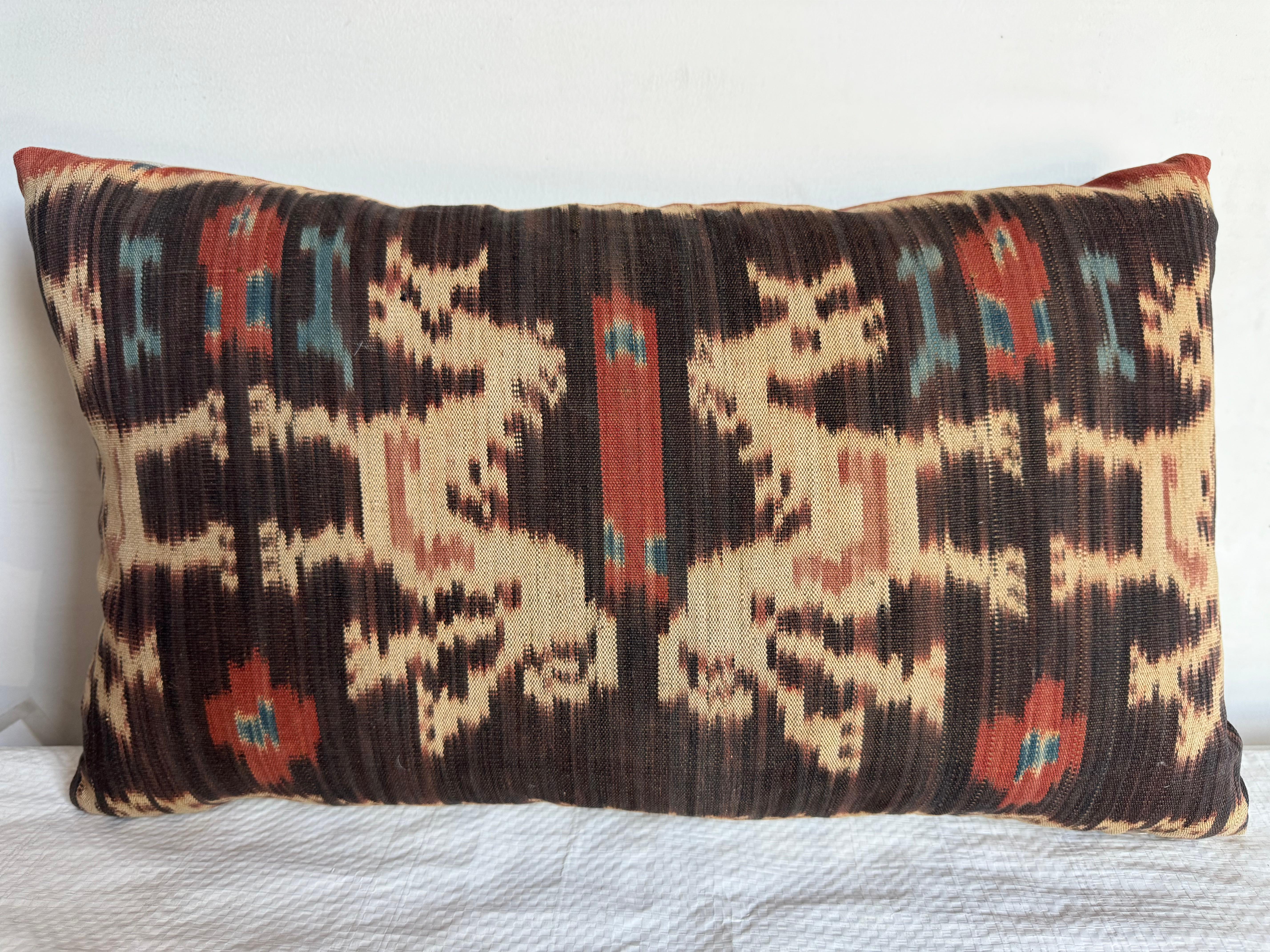 Questo audace cuscino Ikat del 1850 mette in mostra le tecniche di tessitura tradizionali, con un motivo ipnotico dai toni terrosi e vibranti. Il design sorprendente mette in risalto l'artigianato tradizionale con un tocco moderno.

Misurando 18