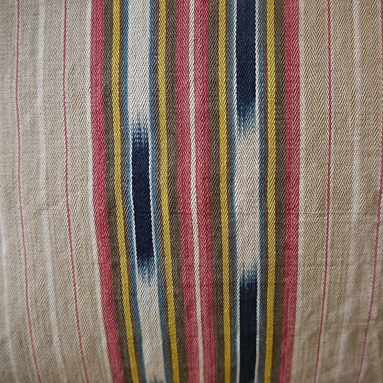 French late 19th century unusual striped ticking linen cushion with an unusual indigo Ikat detail in the stripe. Stripes of lightly faded beige, red and yellow with indigo Ikat floating in between. Self-backed and slip-stitched closed with a duck