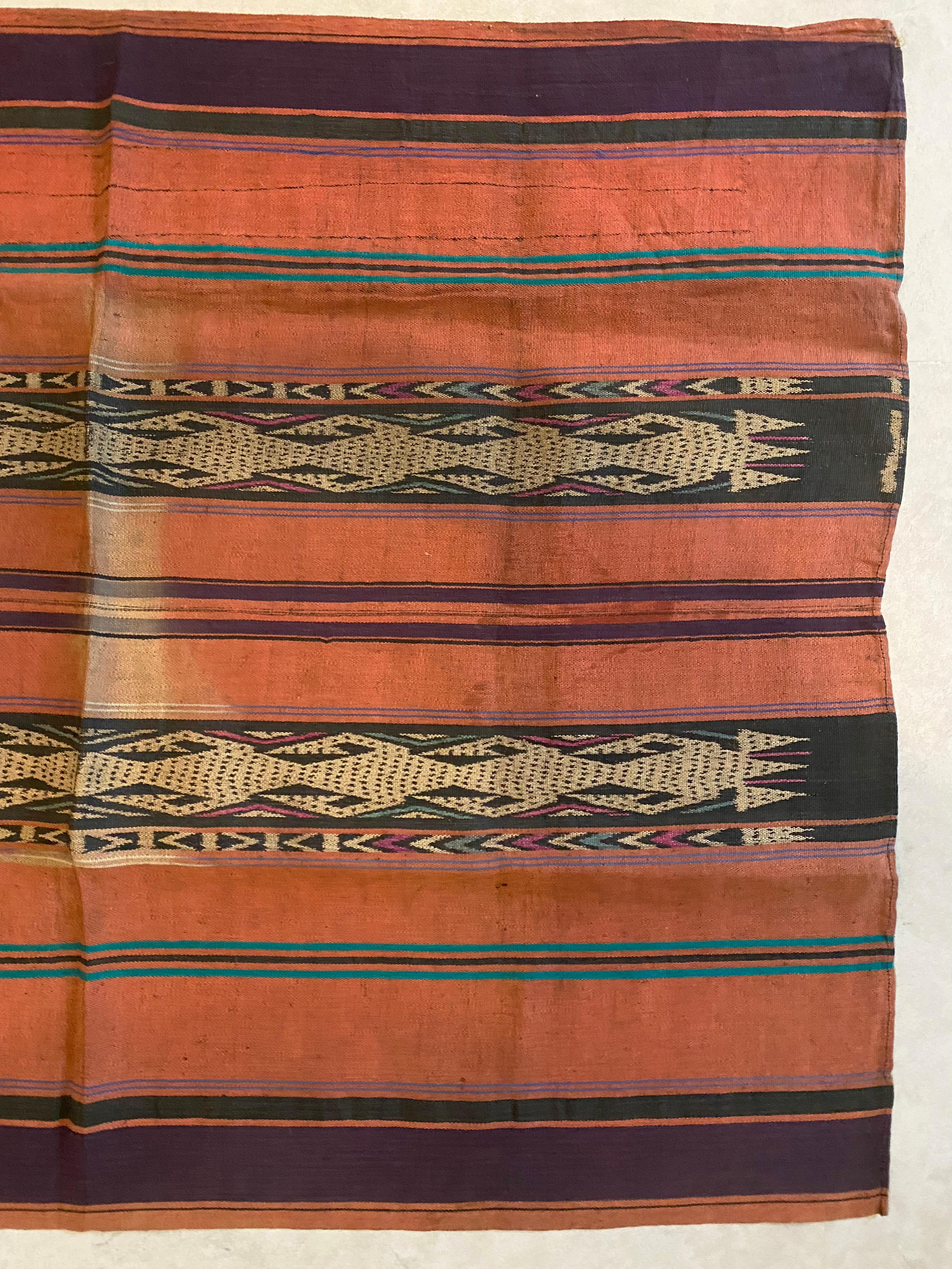 This Ikat textile originates from the Island of Kalimantan, Indonesia. It is hand-woven using naturally dyed yarns via a method passed on through generations amid the Dayak Tribes scattered throughout the island. It features a stunning orange