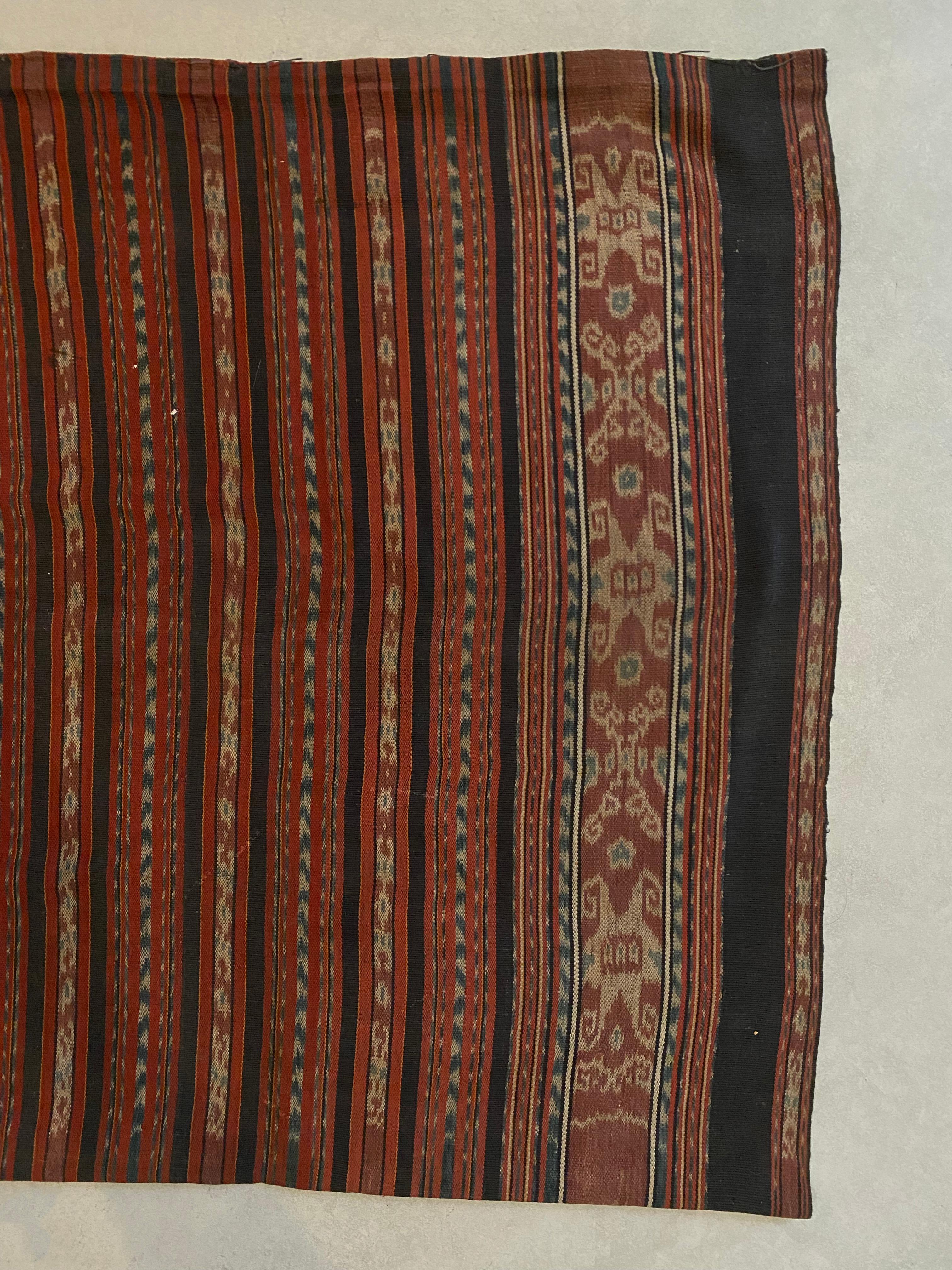 Dieses Ikat-Textil stammt von der Insel Flores in Indonesien. Es wird mit natürlich gefärbten Garnen nach einer seit Generationen überlieferten Methode handgewebt. Dieser Stoff ist schlauchförmig, damit er von den Einheimischen der Insel als