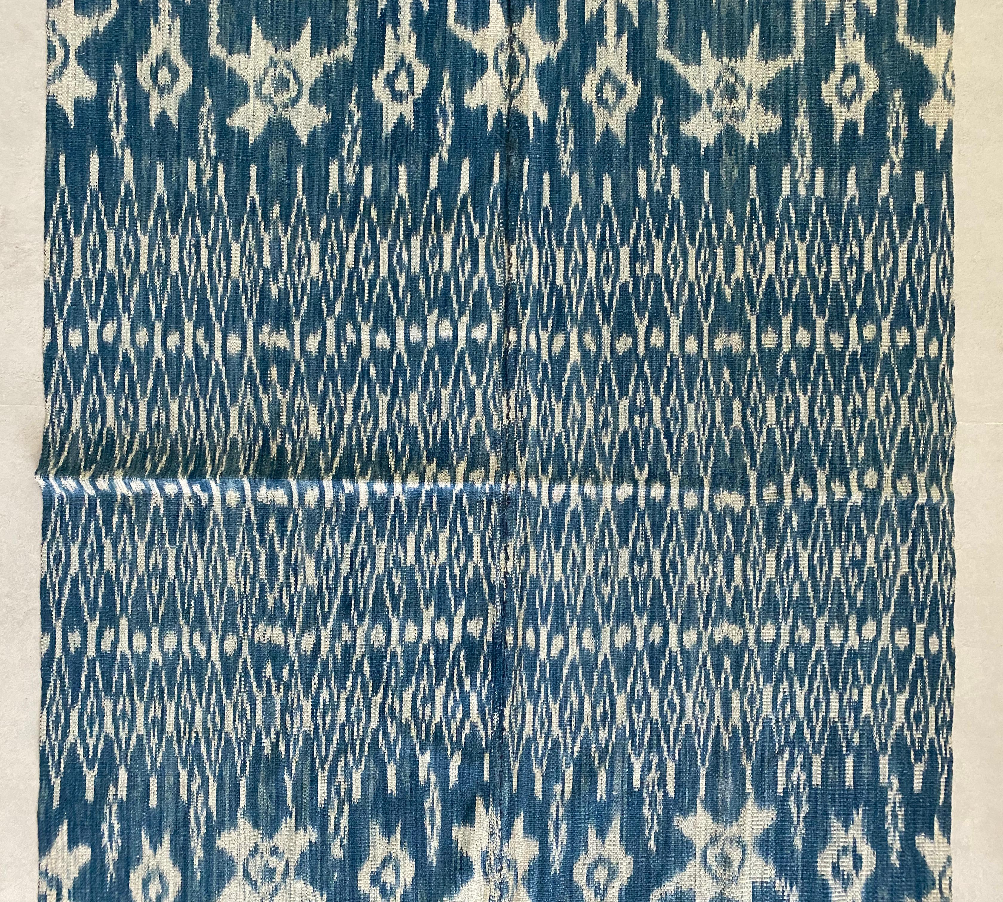 This Ikat textile originates from the Island of Sumba, Indonesia. It is hand-woven using naturally dyed yarns via a method passed on through generations. It features a predominantly blue pigment with chicken motifs and distinct tribal patterns.